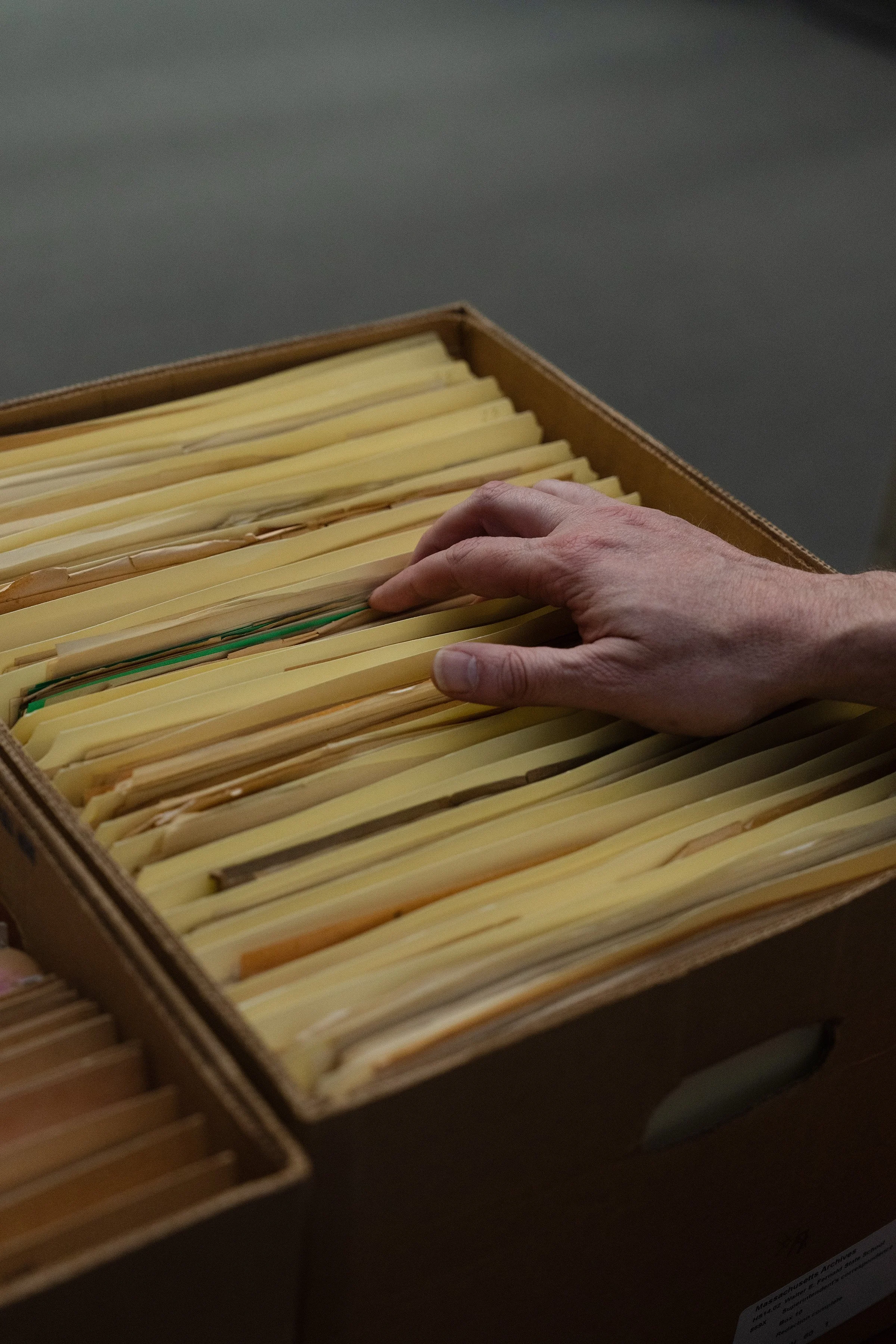 Alex Green filing through a box of records from the Walter E. Fernald State School, at the Massachusetts State Archives in Boston.