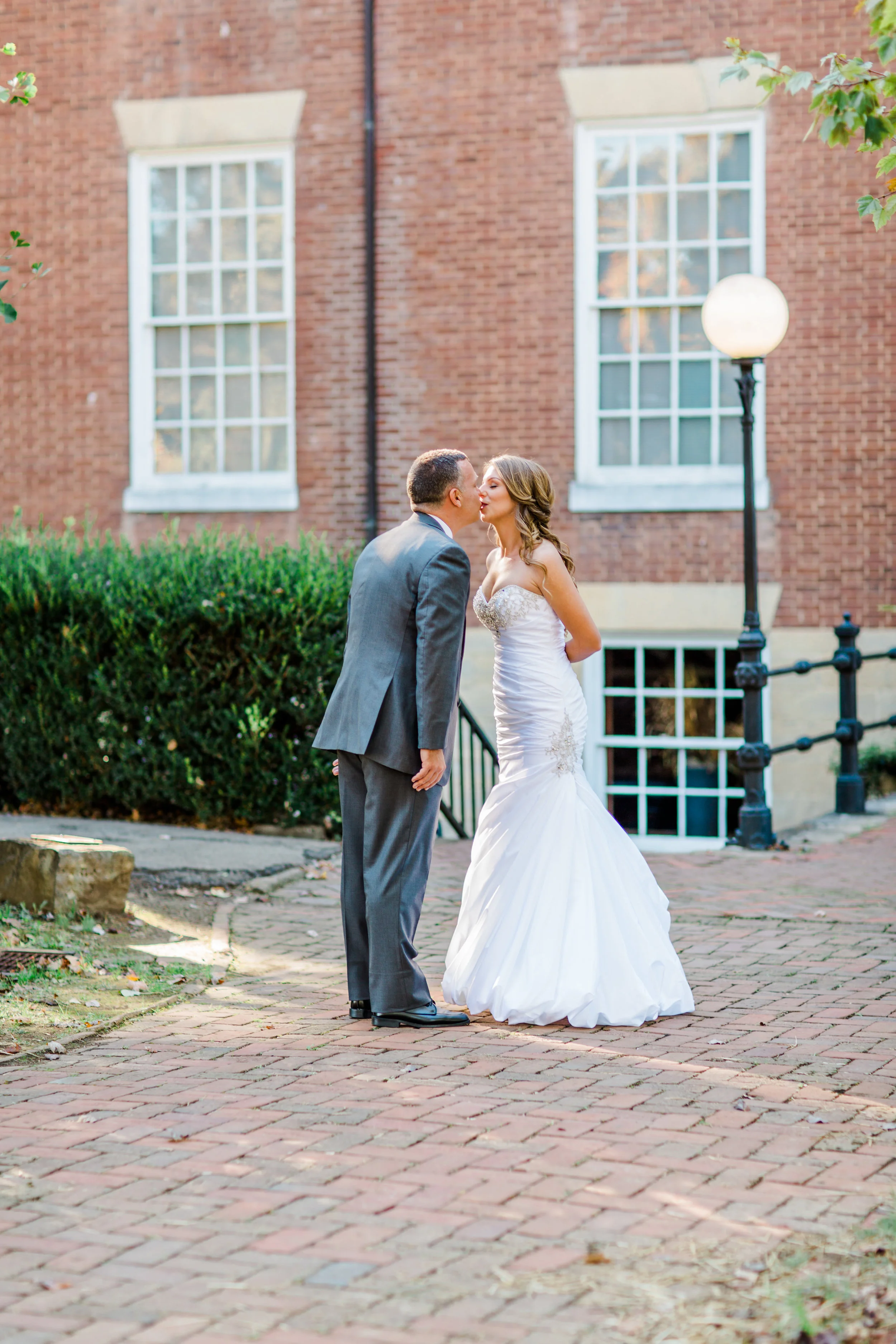 Bride and groom kissing outside Oscar-Getz Museum of Whiskey History during their Bardstown, Ky wedding