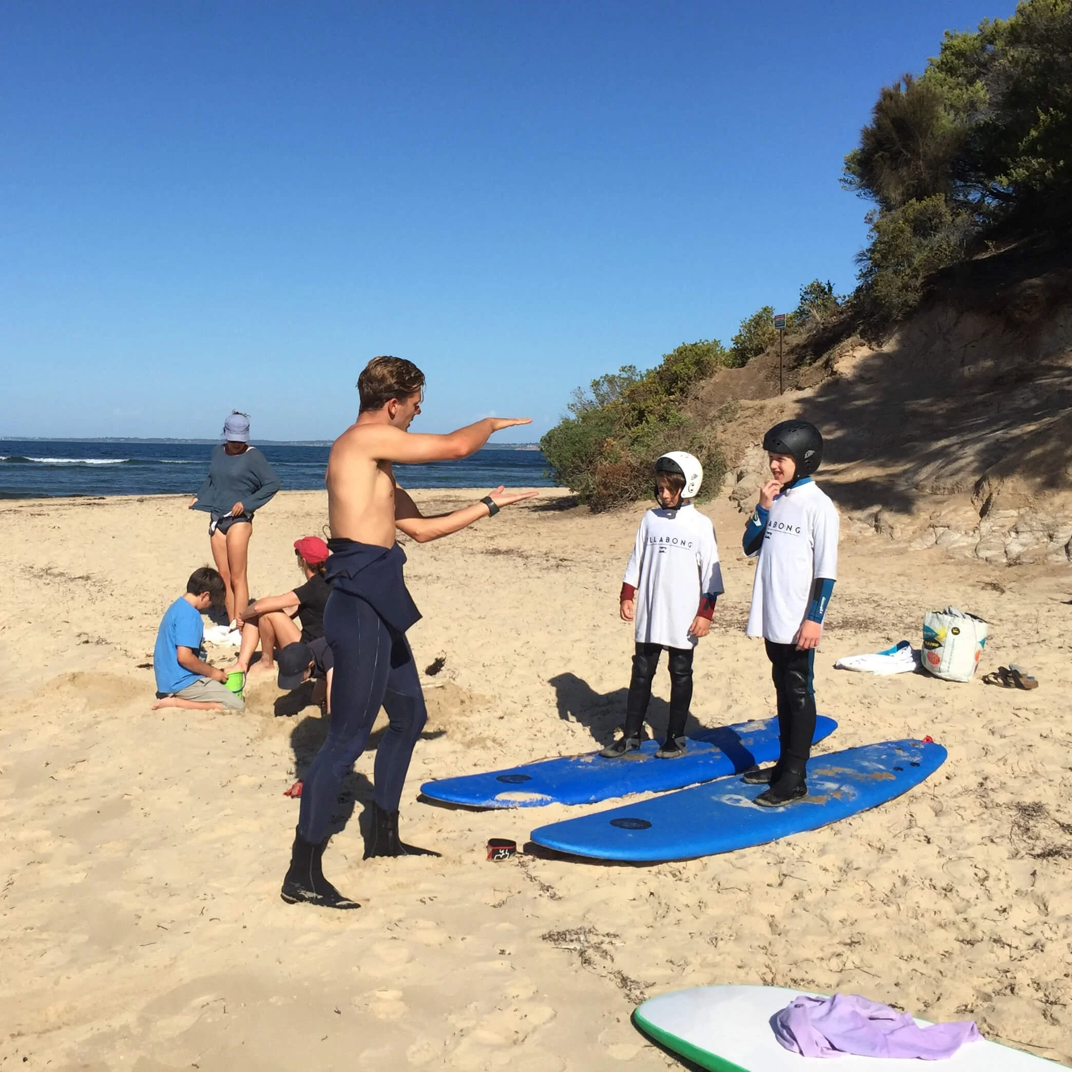 Surf instructor teaching students surf techniques on the beach during a group lesson in Melbourne, Australia.