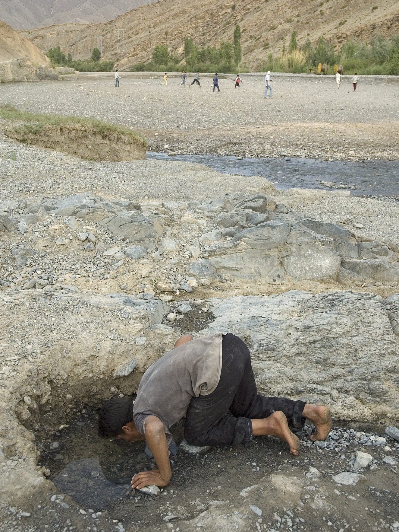  Mohammed drinking from an underground water source on the dry river. 