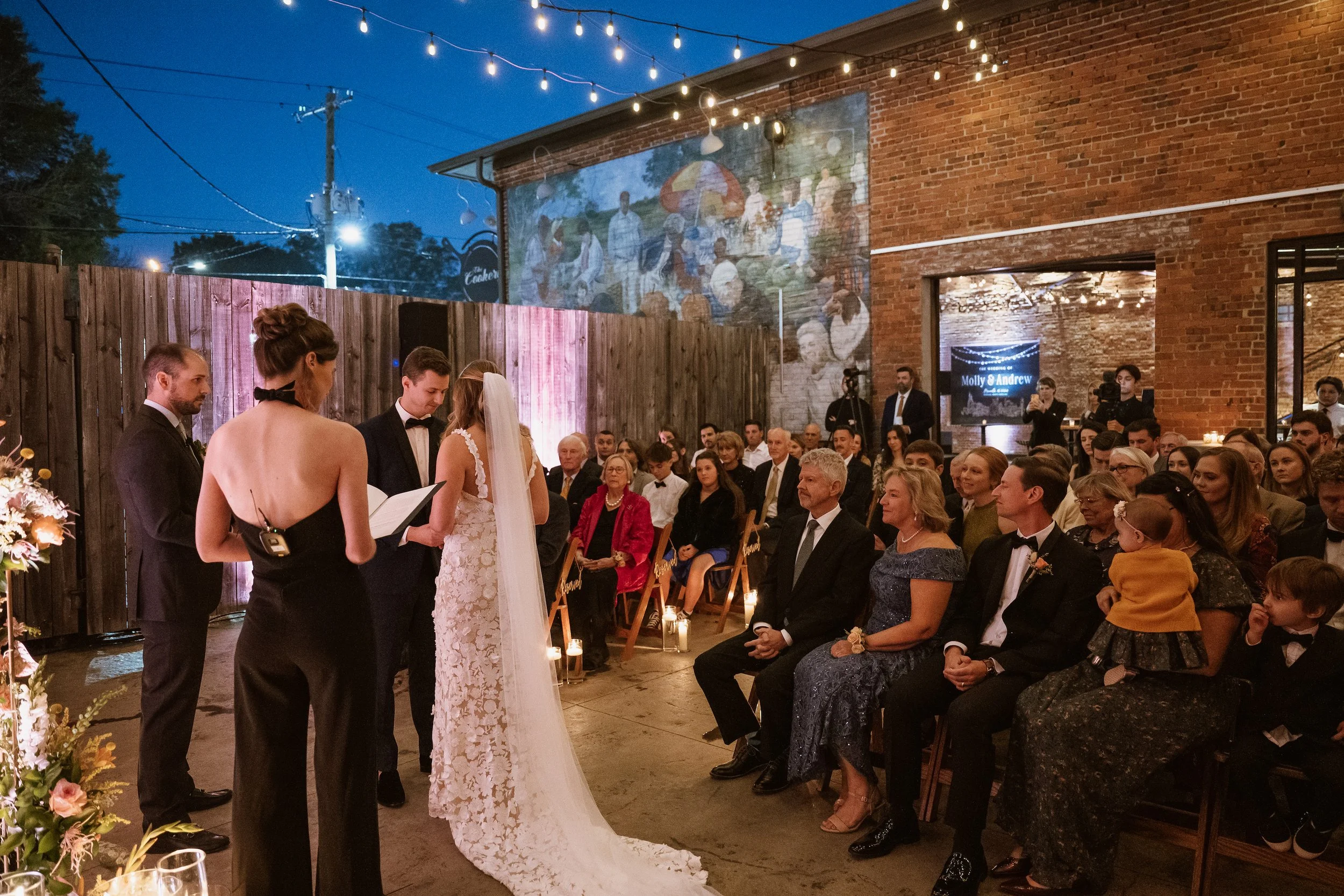 Outdoor wedding ceremony with market lights overhead