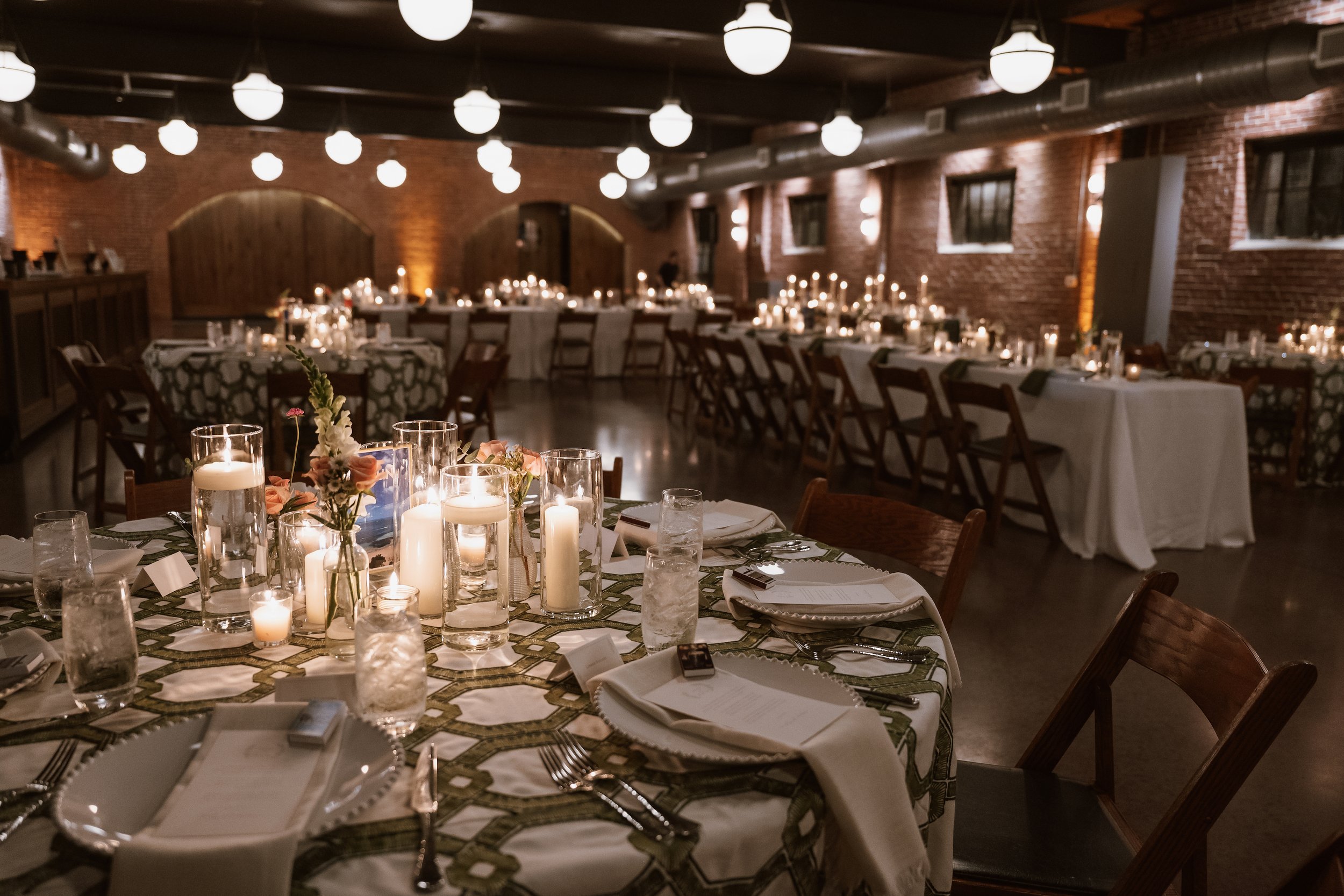Reception hall set up with tables with linens, plates, candles and flowers