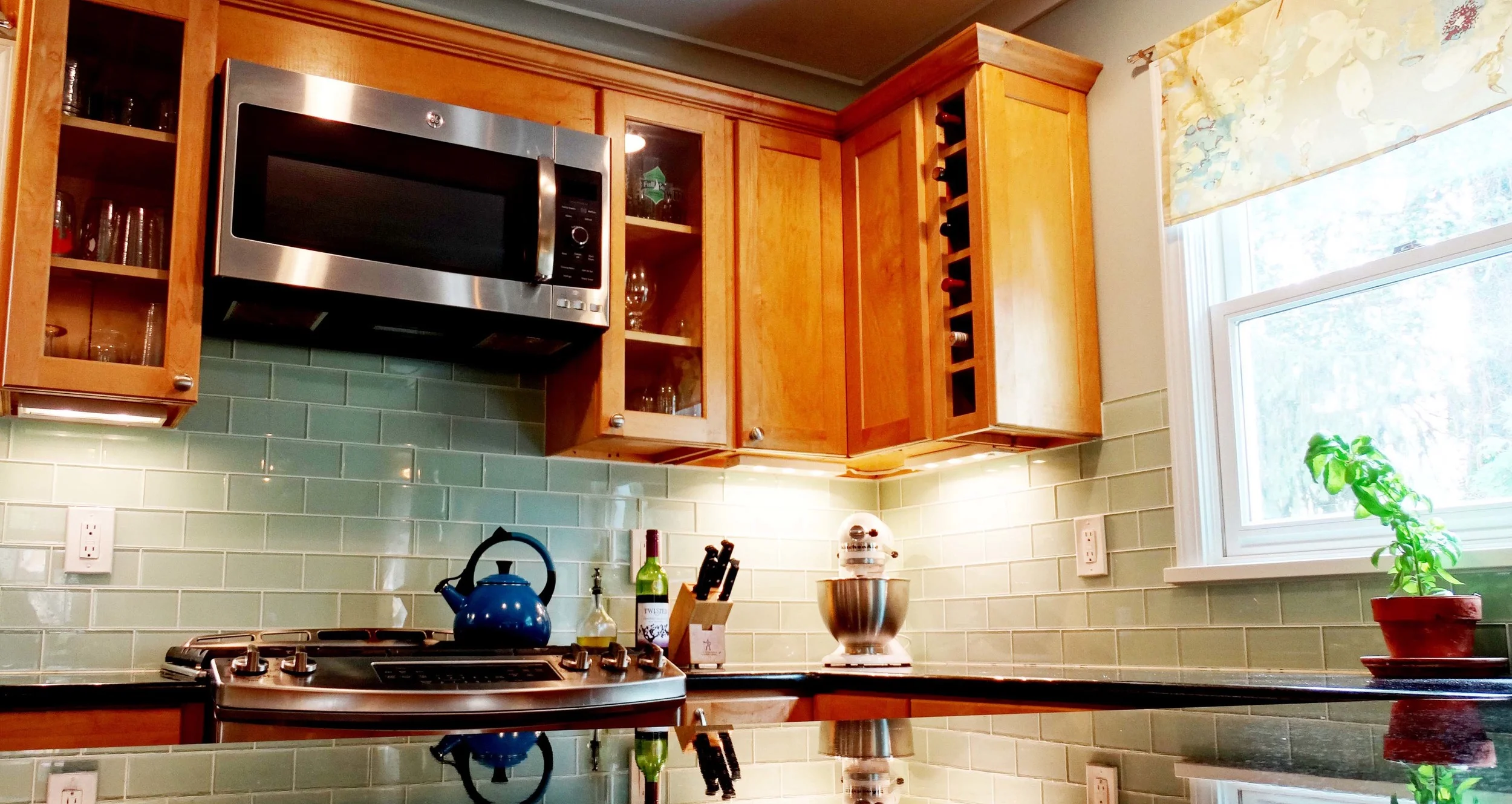 Warm reconfigured and repurposed cabinets, creative wine storage and stainless steel appliances beneath a sweeping granite countertop make a welcoming statement morning, noon and night.