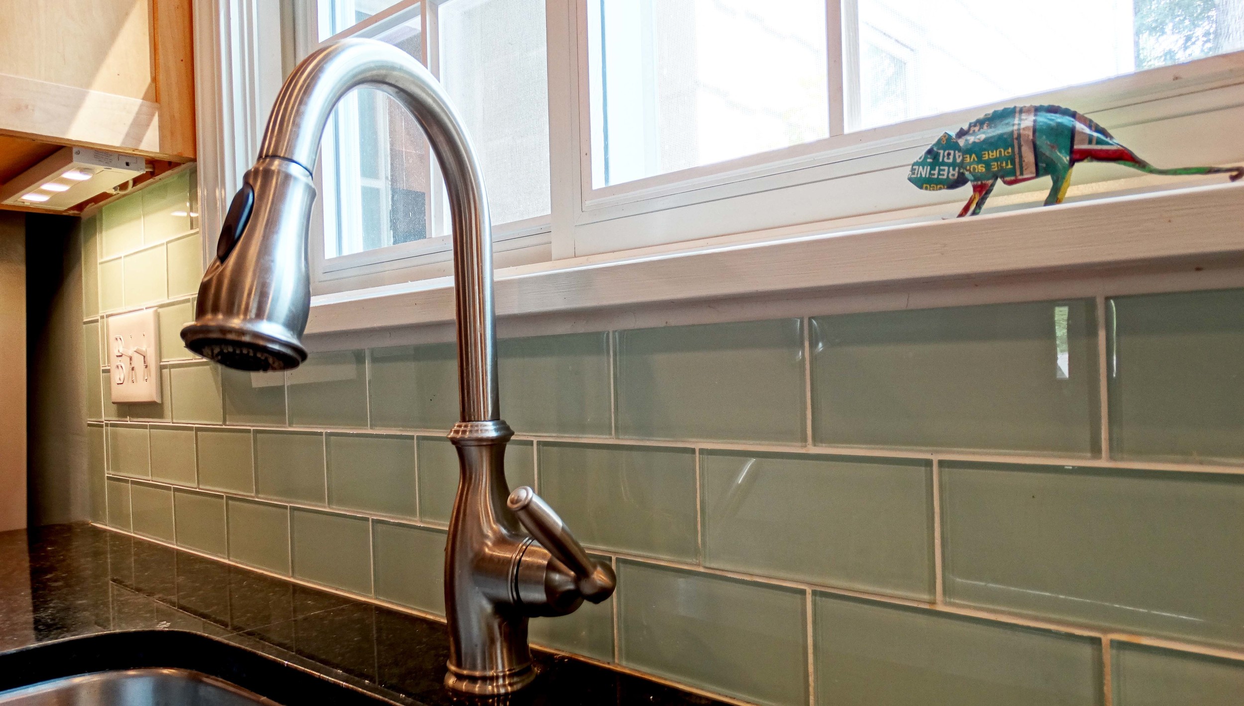Retro glass subway tiles and under counter lighting blend modern and old school touches in this reimagined kitchen.