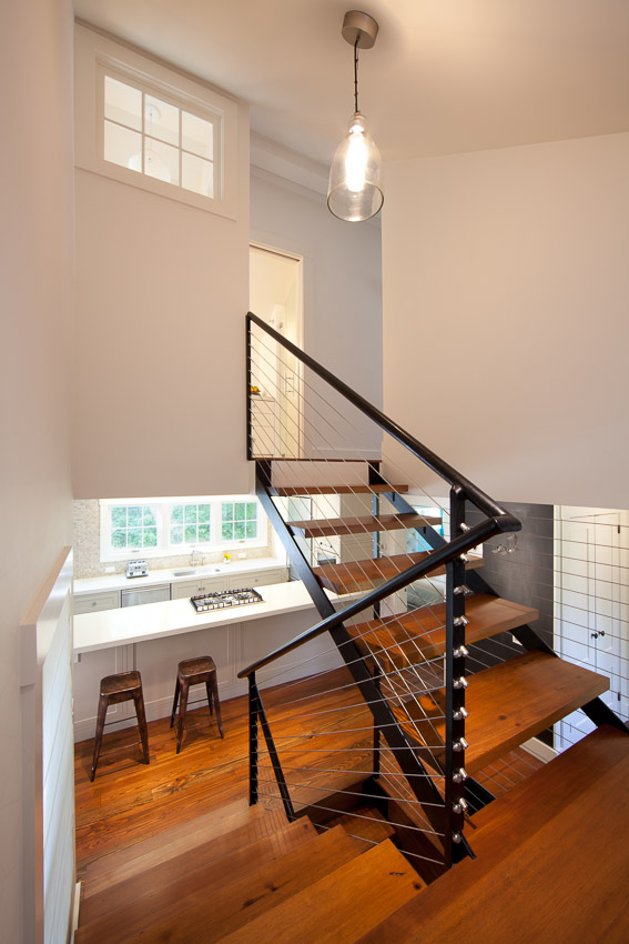 Floating stairs with steel and cable rail leading from second level to basement.