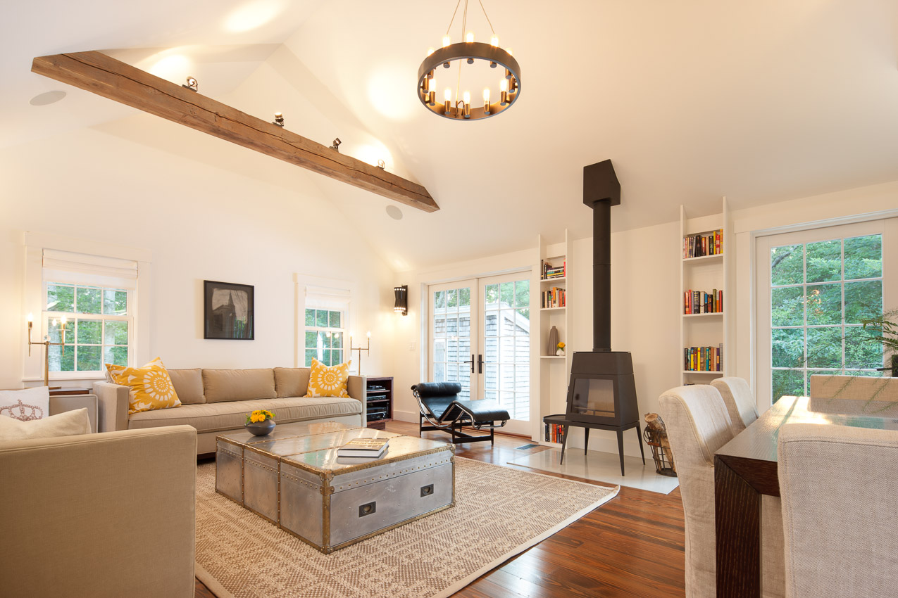 Living room perfectly blends the old and the new with reclaimed wood beam and modern woodstove set on a marble inlay.