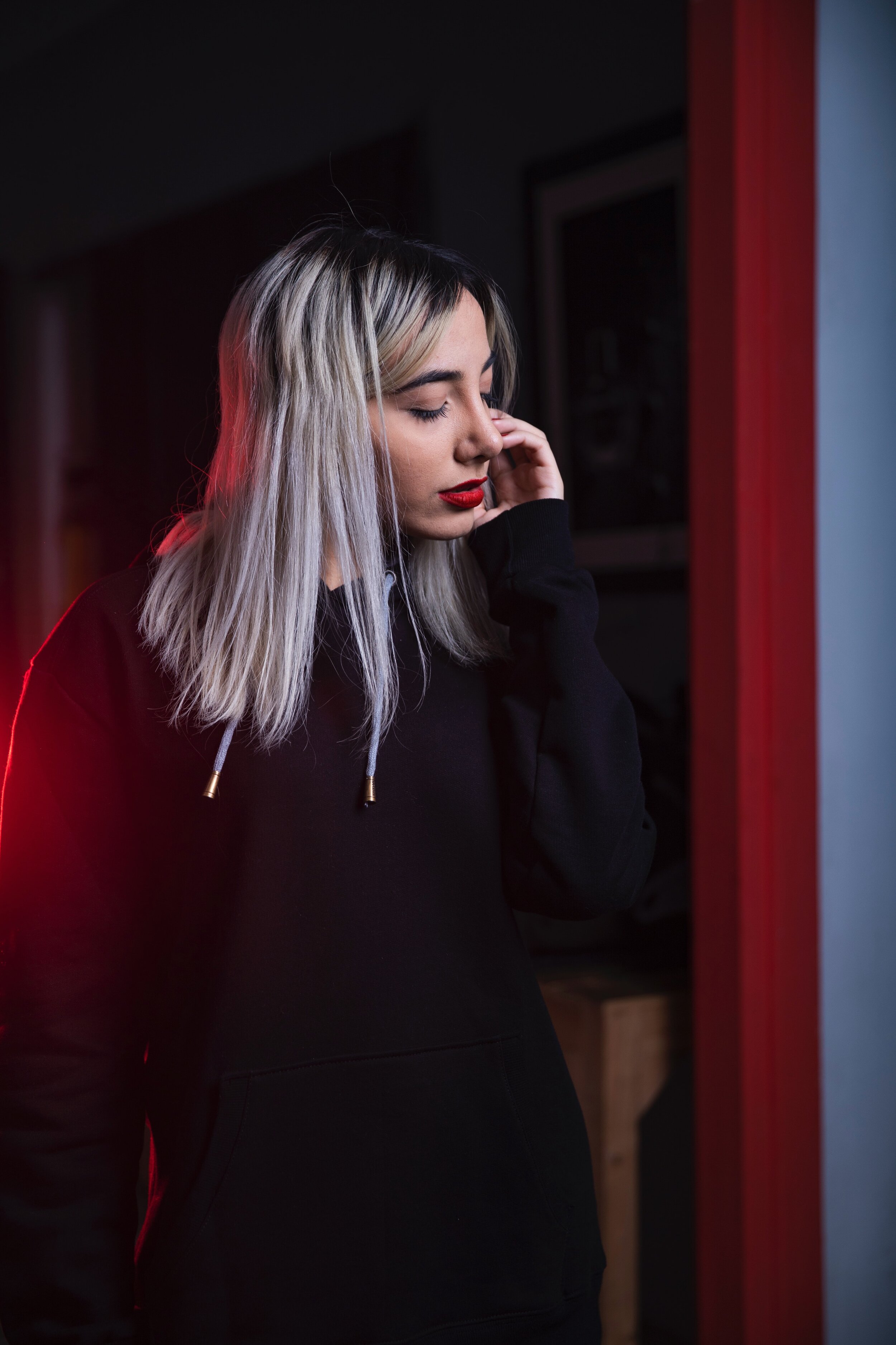 woman looking away in a black sweatshirt. Hand by her face and eyes closed.