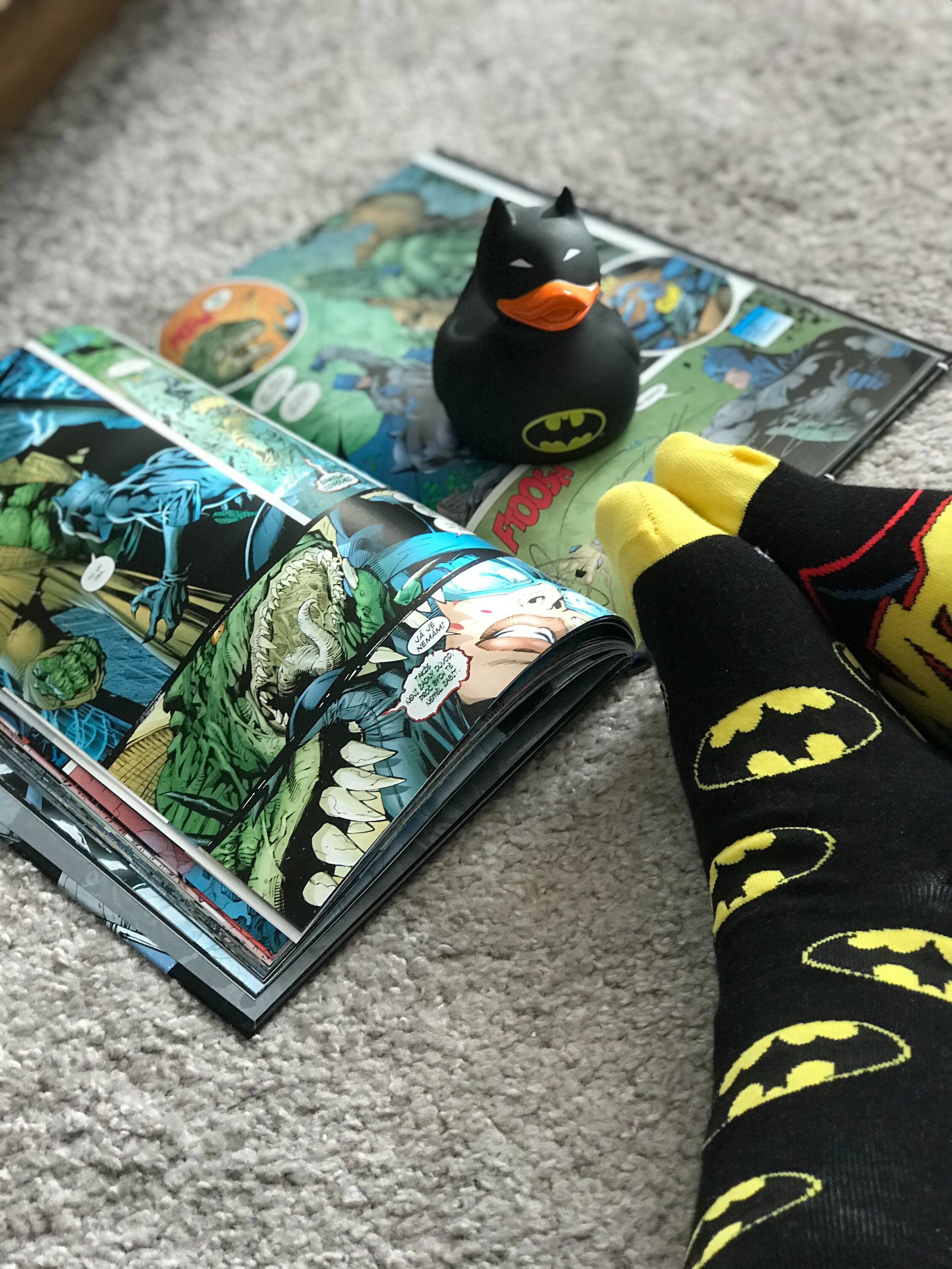 image of a batman duck on a comic book. Feet with batman socks on.