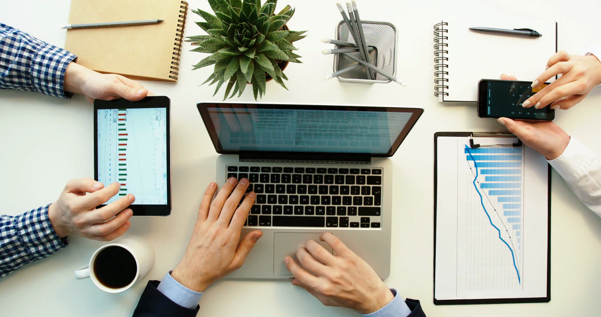 videoblocks-business-team-working-together-at-office-desk-and-checking-a-financial-report-men-using-tablet-and-laptop-computer-and-woman-using-smartphone-and-writing-in-notebook-hands-top-view_hzlfzxurg_thumbnail-full01.png