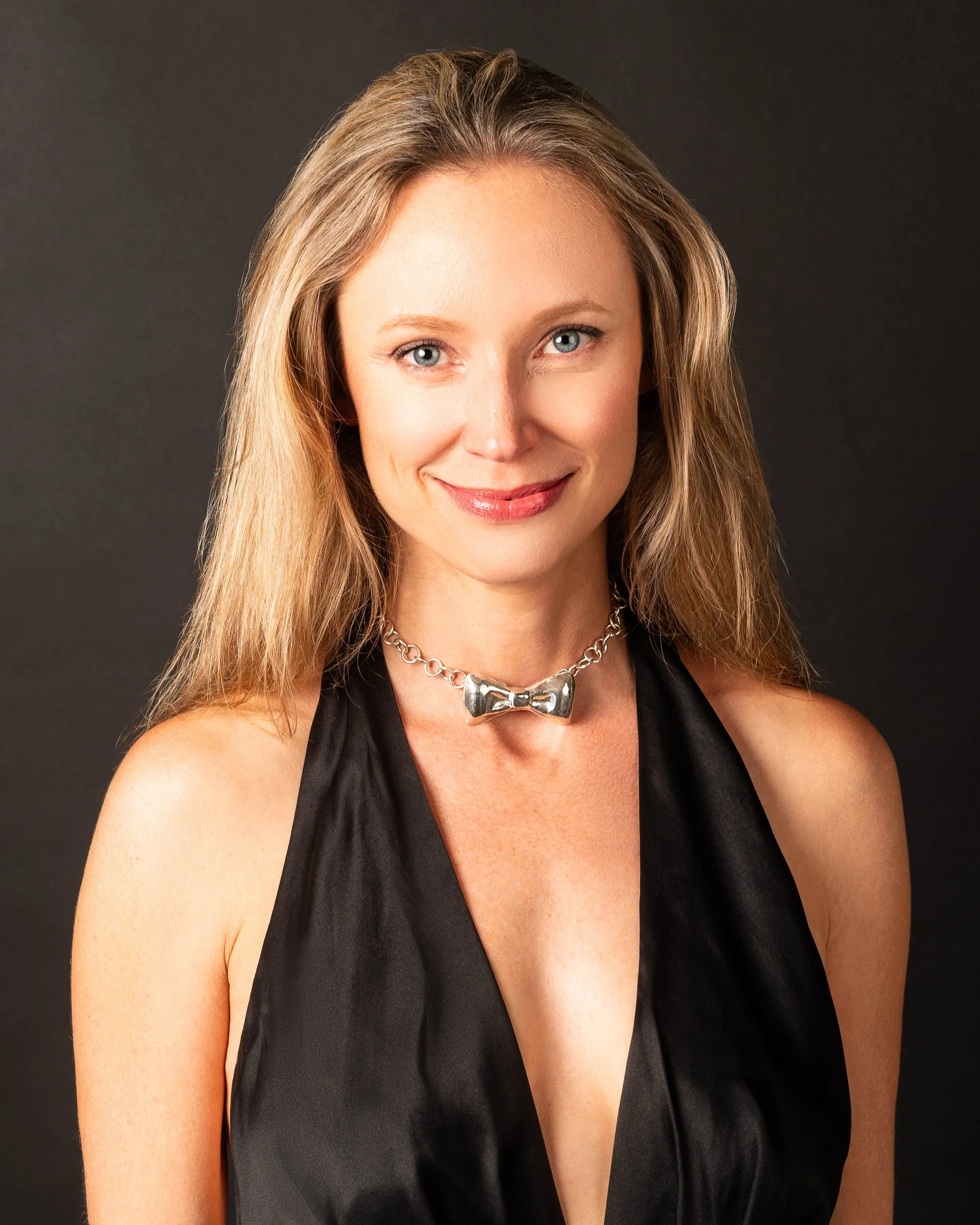white blonde woman wears a sterling silver bow necklace by freddie collier studio in a black gown