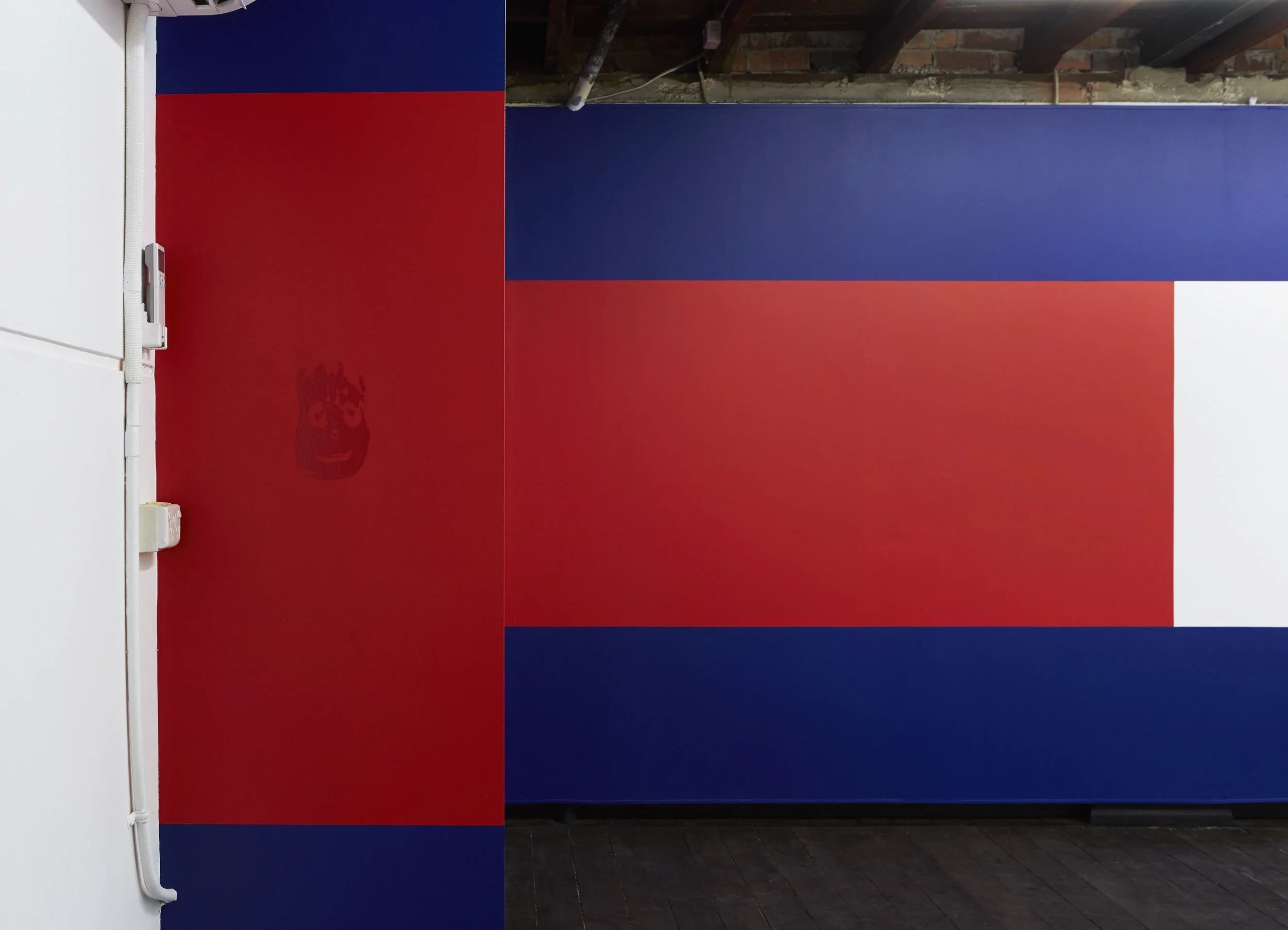 Wilson (foreground), 2017, computer-cut adhesive vinyl scaled to the dimensions of the artist’s hand, unlimited edition; and Flag 2 (background), site-specific acrylic wall painting, installation view, Coconut Republic , Firstdraft, Sydney. Photo: Zan Wimberley. Copyright JD Reforma