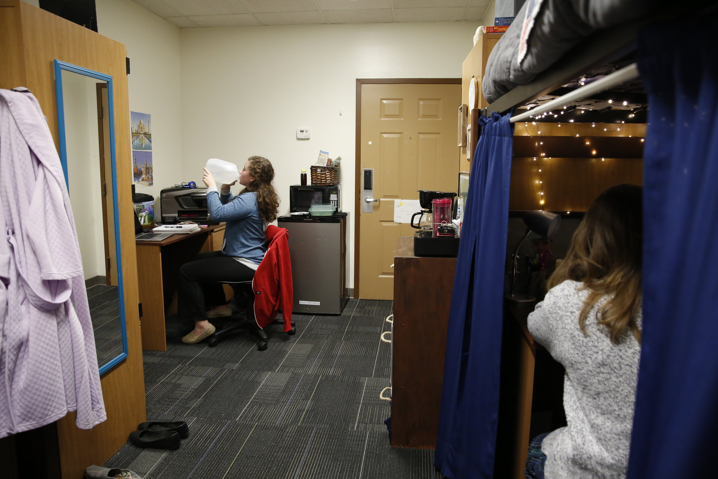  Grace drinks directly from a water jug in her dorm room. It’s a habit that she picked up from her dad. &nbsp; 