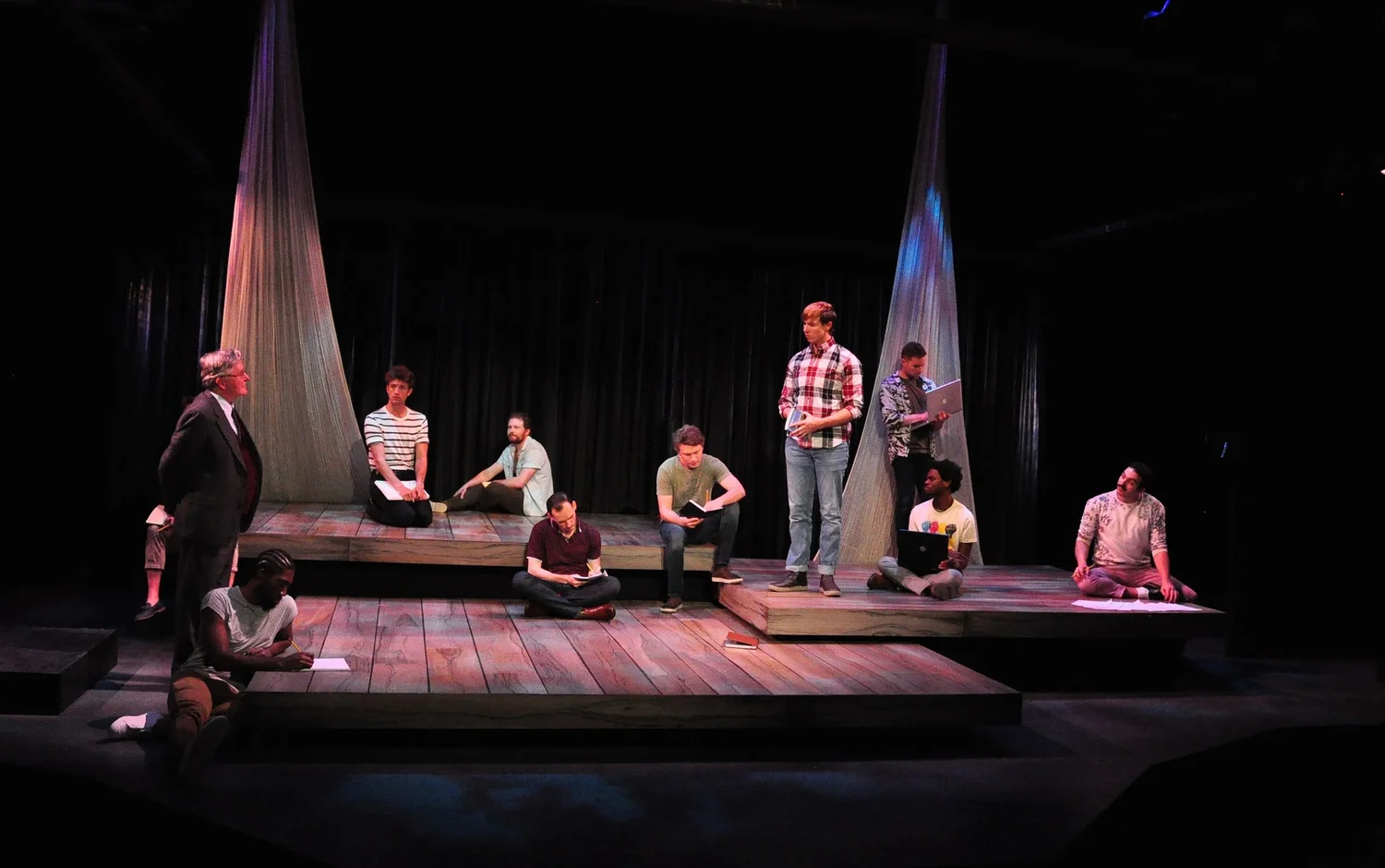 The ensemble on the stepped wooden stage in Unicorn Theatre’s production of The Inheritance