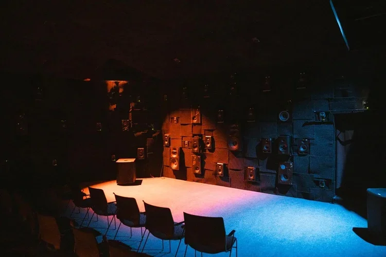 An intimate Sound Mandala room with loudspeaker walls illuminated in amber and blue