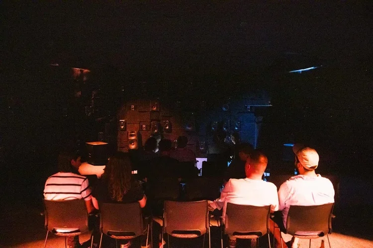 Listeners seated inside Sound Mandala facing the illuminated loudspeaker walls