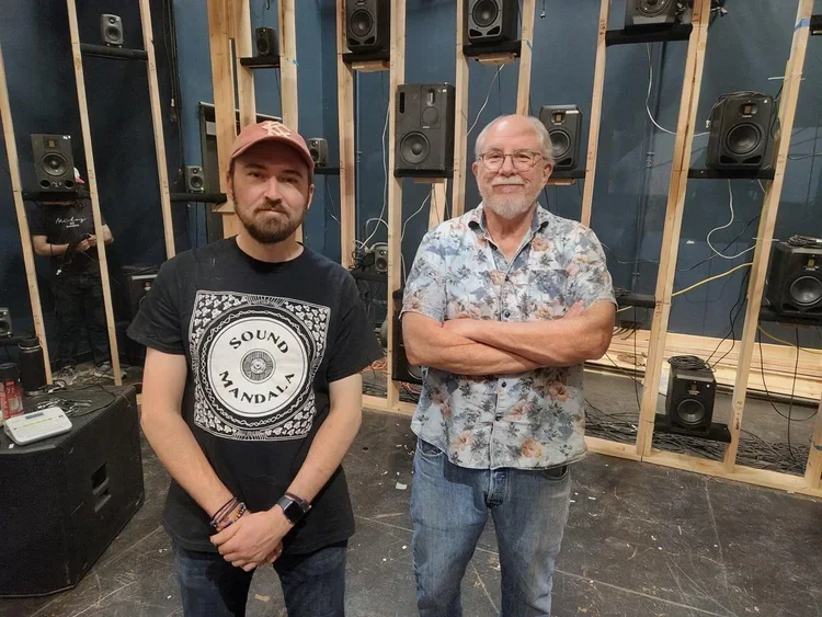 Jon Robertson and a collaborator among the loudspeakers and timber framing during construction