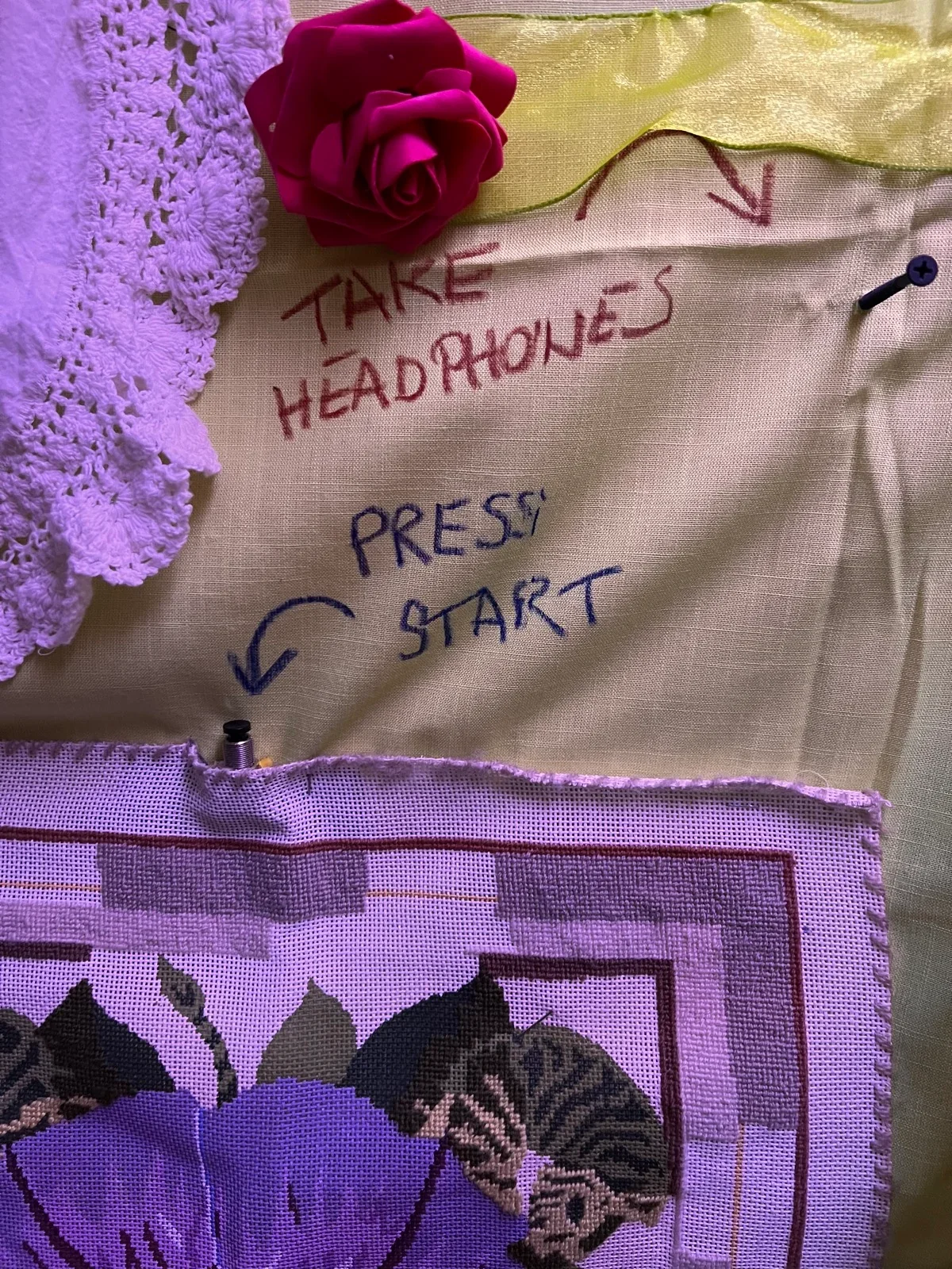 The physical start button beneath handwritten instructions to take headphones and press start