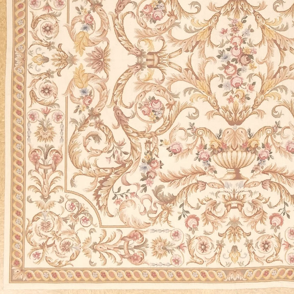 corner detail of new square cream and gold handwoven needlepoint rug