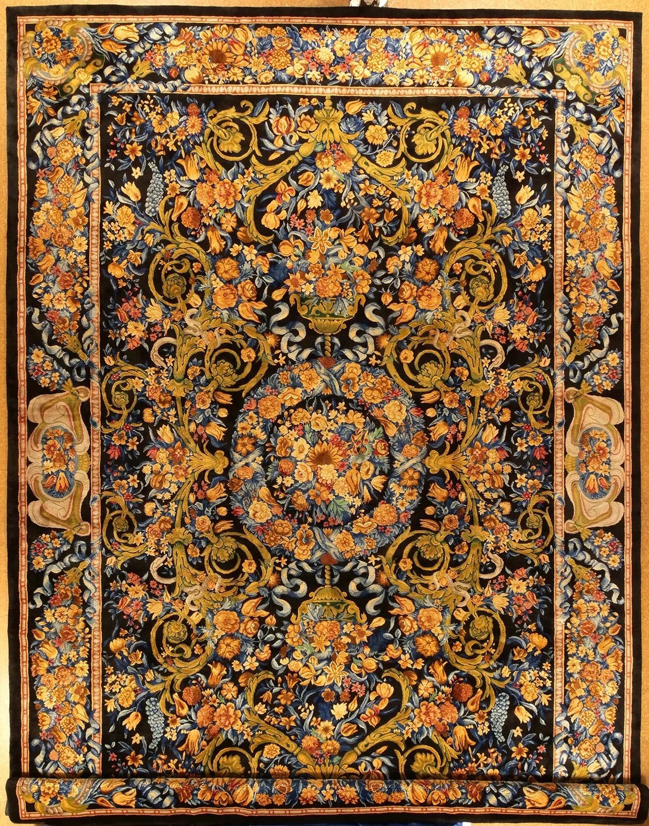 Louis XIII  Savonnerie style rug with intricate floral and vine patterns in shades of orange, gold, blue, and green on a black background.