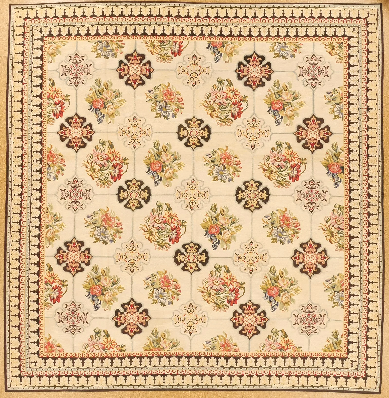 An Aubusson floral patterned area rug with a beige background, featuring pink, blue, and red flowers, arranged in a symmetrical design with decorative borders.