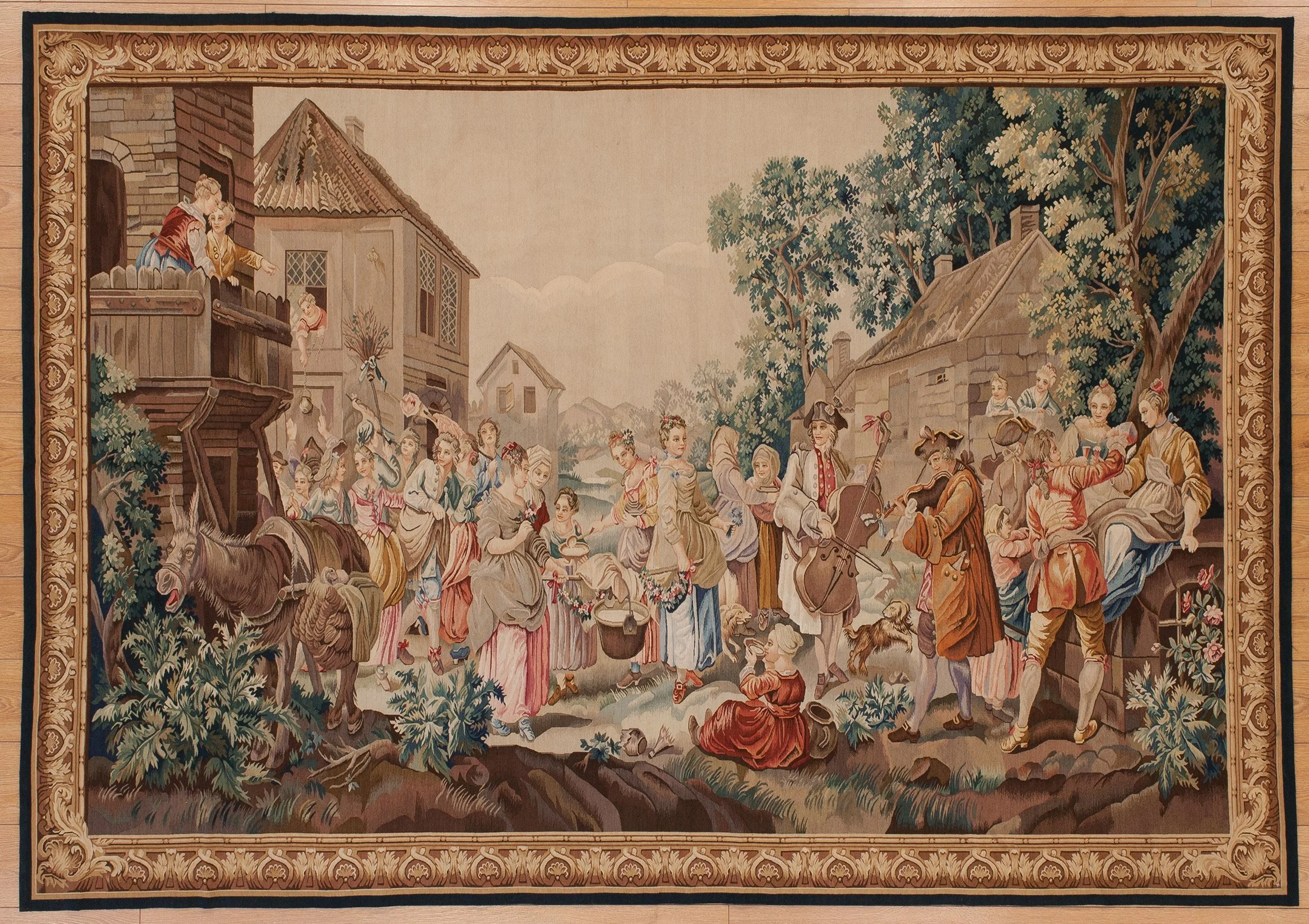 A traditional tapestry scene depicting a lively village with people participating in a folk celebration or dance. Men, women, and children are dressed in historical clothing, playing musical instruments, dancing, and socializing among houses, trees, and a river.