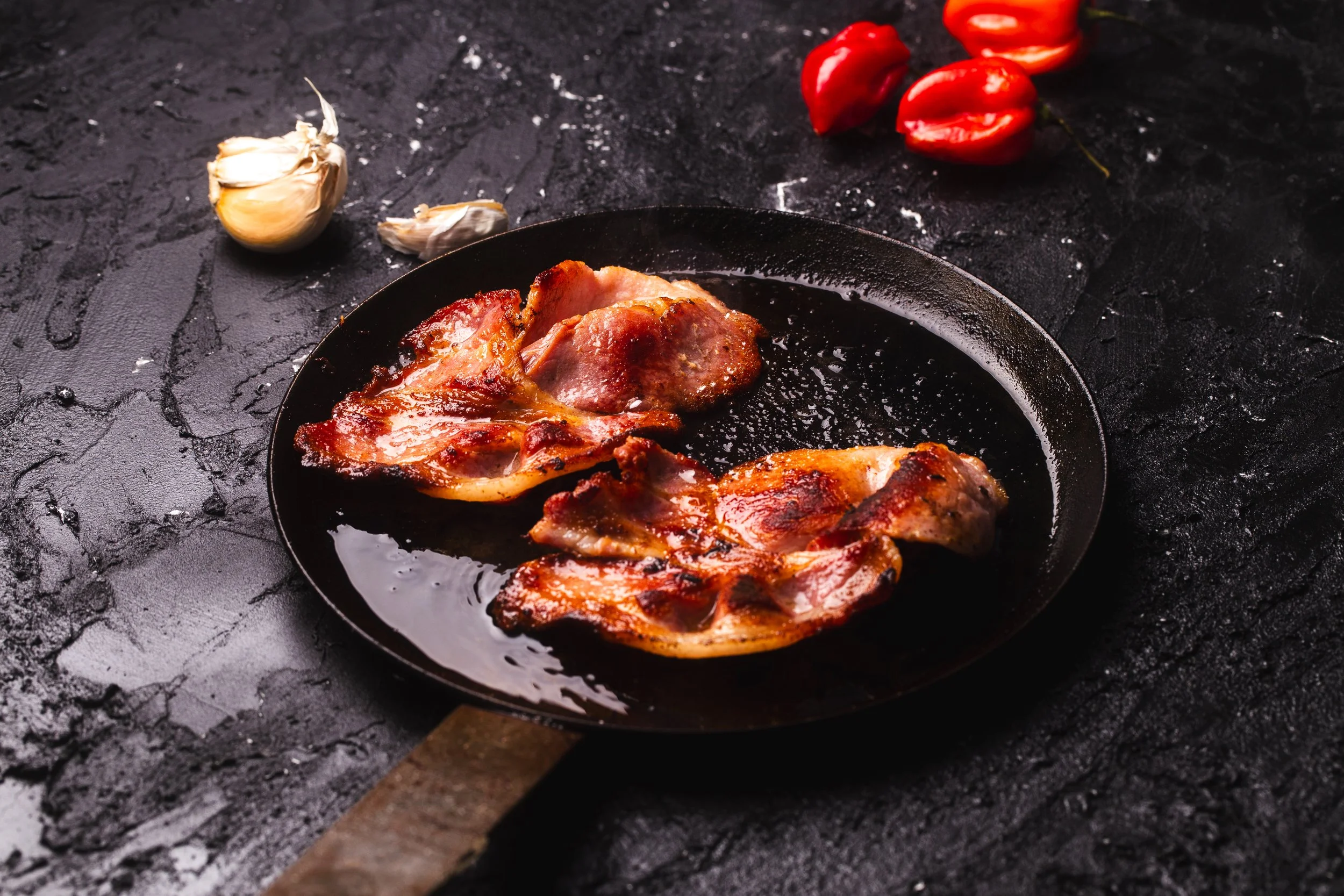 Cooked bacon in pan.  Dark and moody style.