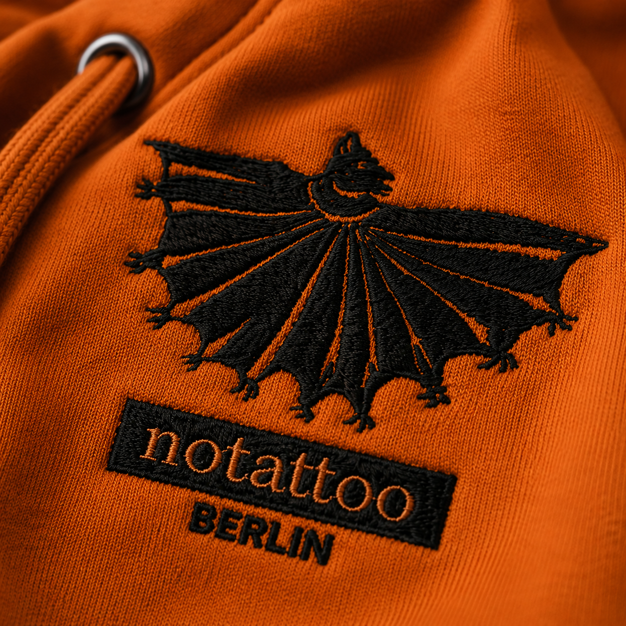 Close-up of embroidered medieval bat artwork on Adobe Yellow hoodie by noSHBerlin, inspired by medieval animal imagery, tattoo culture, and historical drawing.