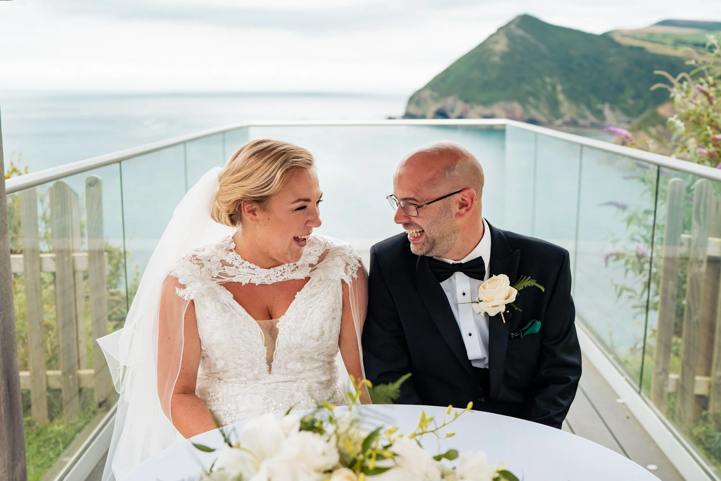 devon wedding - bride and groom sat looking at the sea