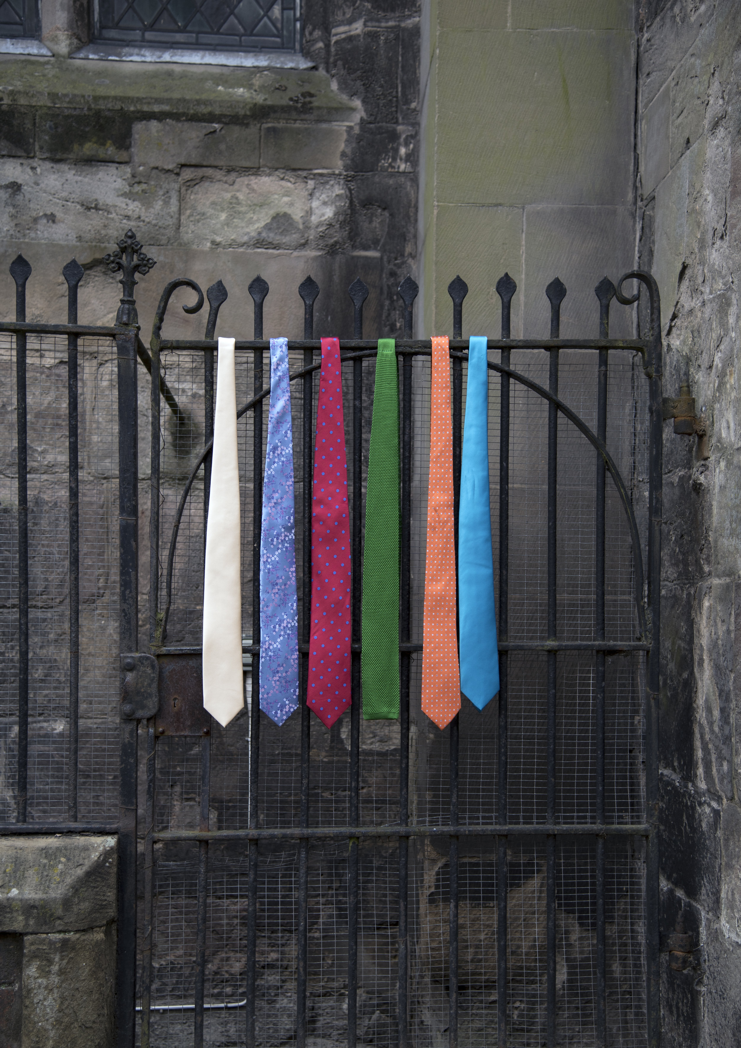 Row of colourful men's ties haning off railings in Hereford.jpg