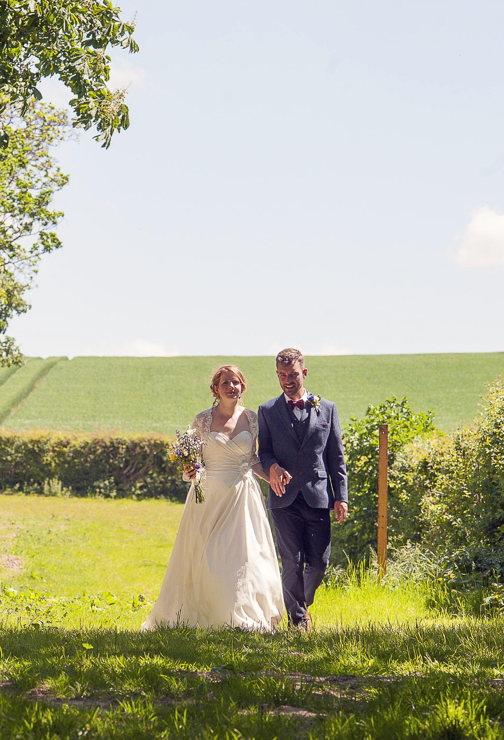 Bride and Groom strolling through a summer field.jpg