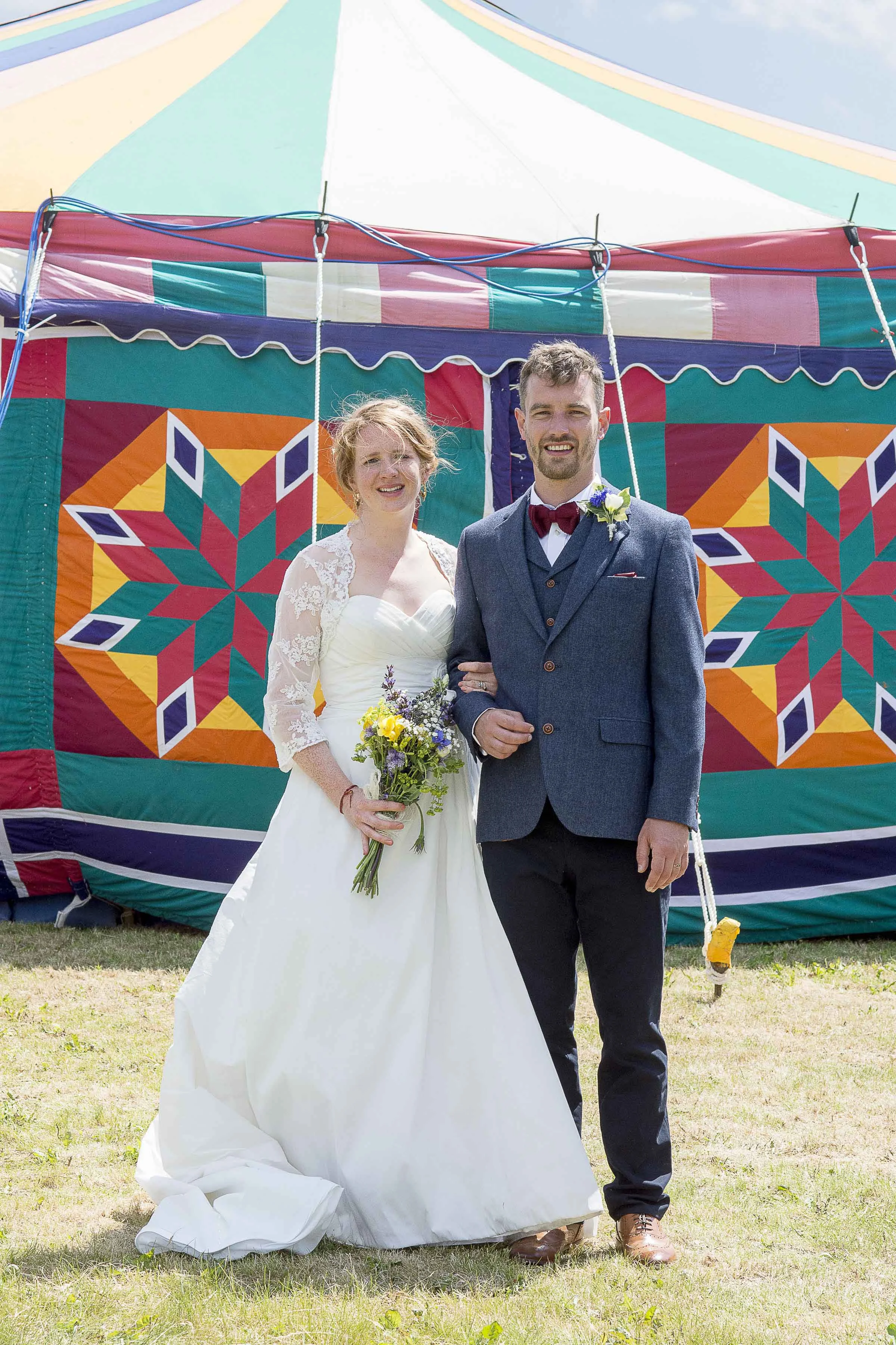 Bride and groom standing in front of a circus tent