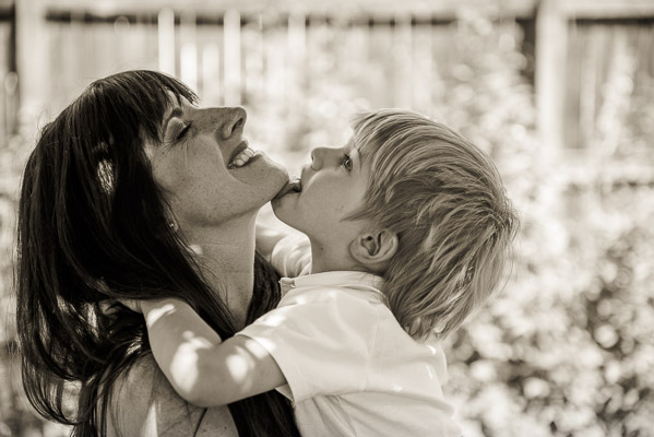 Little boy licking his mother's chin.