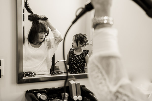 Grandma does her hair while granddaughter looks on.