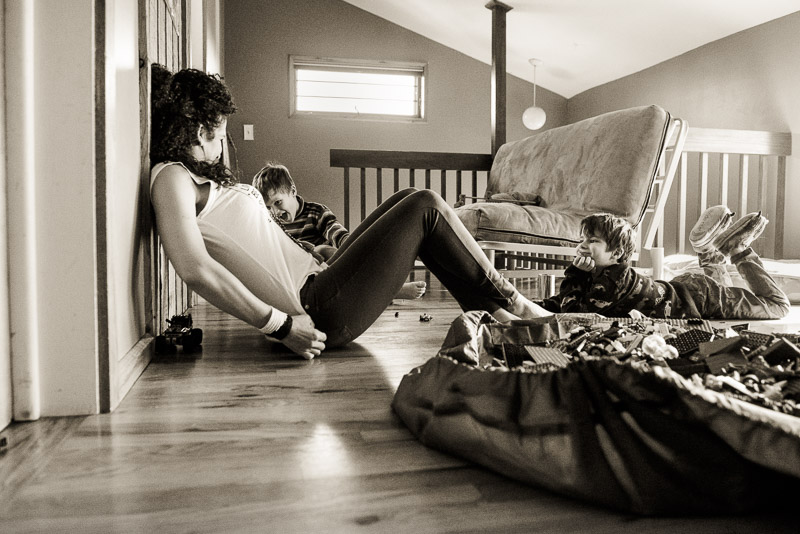 Black and white photo of kids playing cars using Mom's back as a bridge.