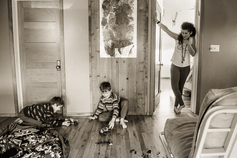 Mom looks on as boys play on the floor.