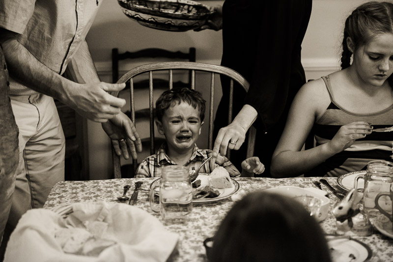 Little boy is crying at the dinner table.