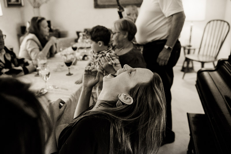 Woman laughing uproariously at the dinner table.