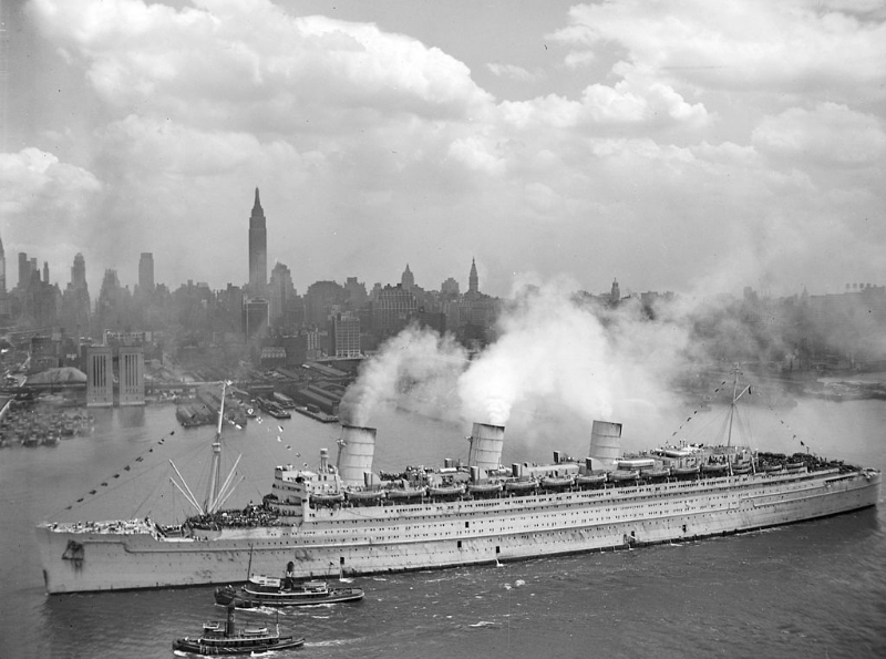 Queen Mary arriving in New York carrying thousands of serviceman home following the end of World War II. To this day, she retains the record for the most souls ever carried aboard a single vessel: 16,683 (including crew) on a crossing from New York to Greenock in July 1943. (Credit: Public Domain )