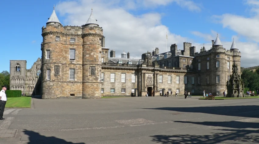 The Palace of Holytoodhouse on a clear day with visitors walking about. Image Credit: Oliver-Banjoch via Wikimedia Commons CC