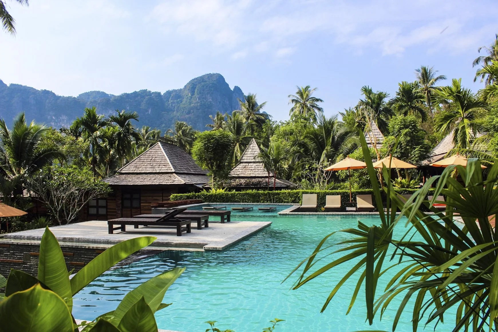 Hotel pool with bright aqua water, surrounded by palm trees