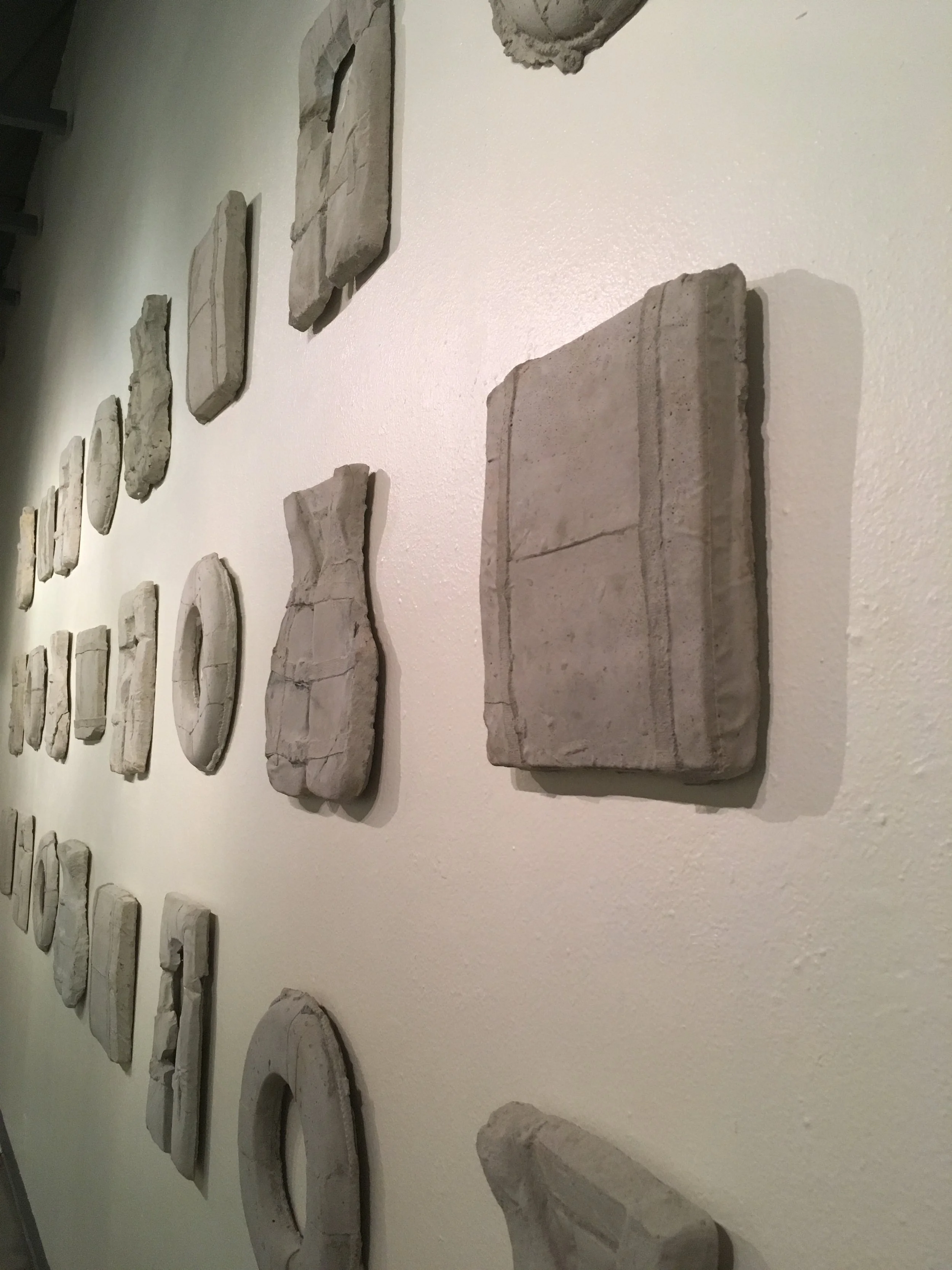 Current Cement / 7x20’ / 2017 / 24 cement life preservers in total cur·rent 1. belonging to present time; happening or being done now. 2. a body of water moving in a definite direction. Current is based on the ongoing international migration of people crossing the Mediterranean Sea trading out one desperate situation for another. Based on recent UN numbers from the beginning of 2015 through October of 2016 there has been an estimated 7640 people who have drowned or gone missing trying to make the voyage. These numbers have been determined to be the lowest estimate possible. With that as a baseline number, each life preserver presented here represents, at the very least, 318 deaths in that time. With an estimated 37% of people making the trip being children, I cannot as a father, fathom the desperation it would take to have this be the best solution. The material and presentation here in the gallery is a memorial to those who have perished and a reminder of the hundreds of thousands of people who live in peril everyday and whose only “fault” was being born in a specific geographic location.