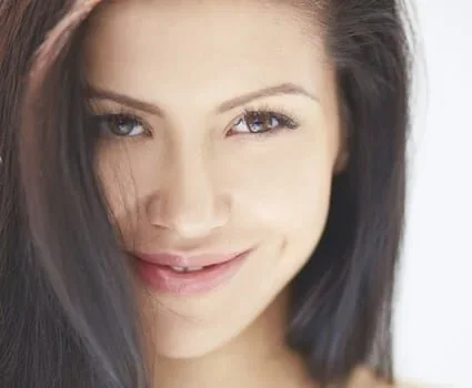 A brunette woman looks flirtatiously at the camera.