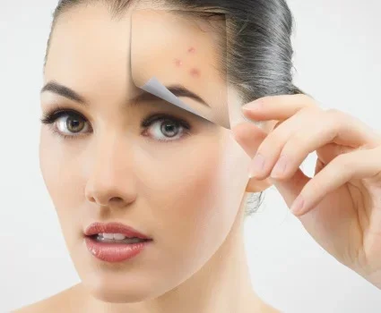 A young woman focuses on acne spots on her forehead.