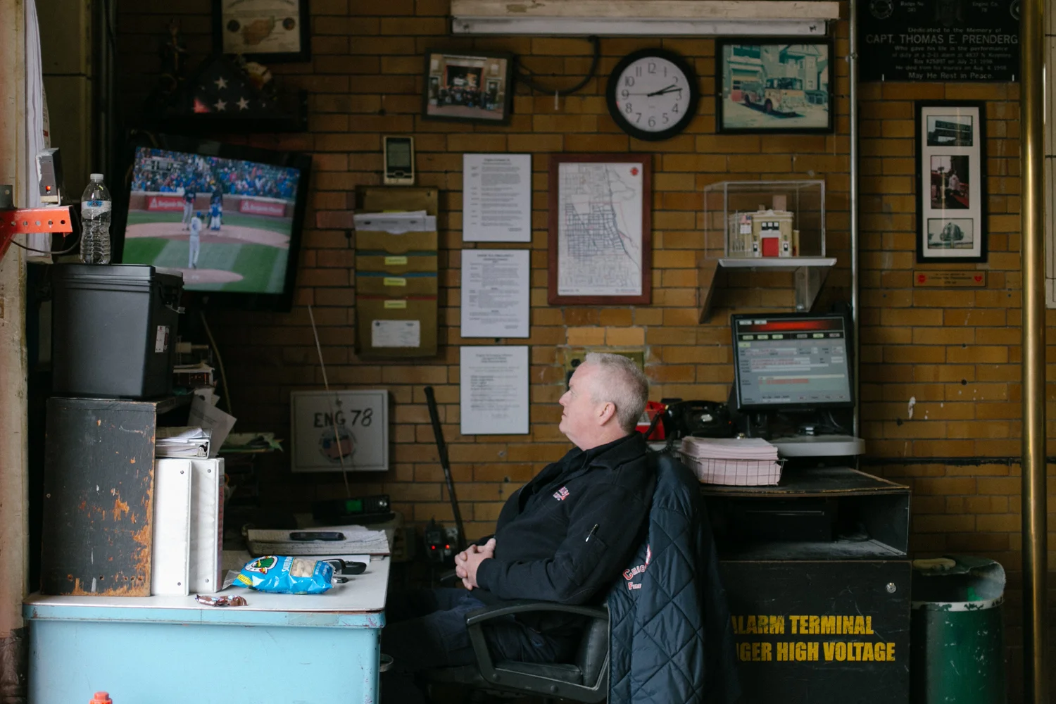 John, a 20 year veteran of the Chicago Fire Department takes a break to watch the Cubs game. The station is across the street from Wrigley Field. They can hear the action but can't see it. 5/25