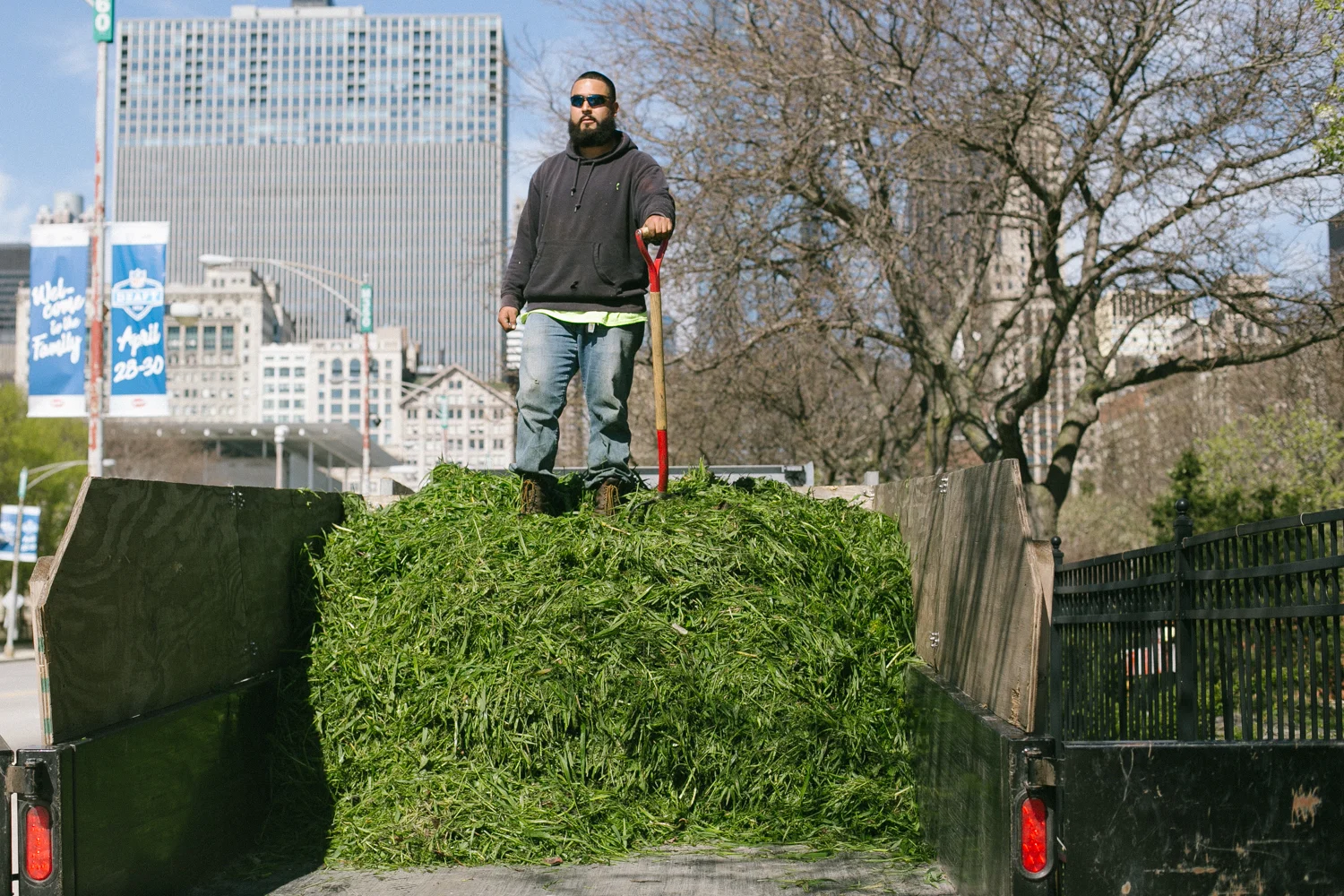 Ramera stands on top of a trailer load of grass clippings after smashing them all down. He has a full day of weed whacking ahead of him. 23/24