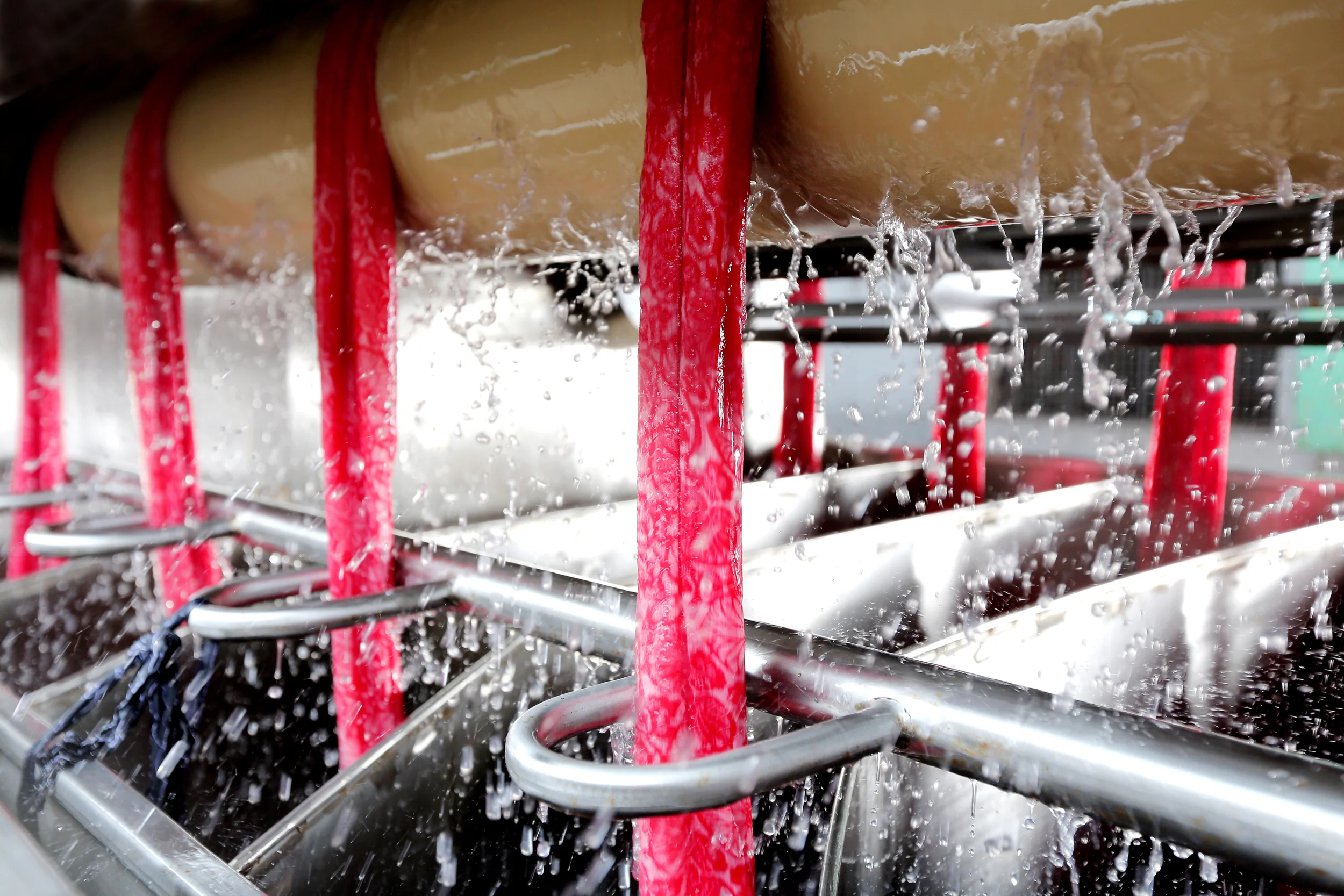 Underwater shot of red support bars and white surfboards being washed by water spray.