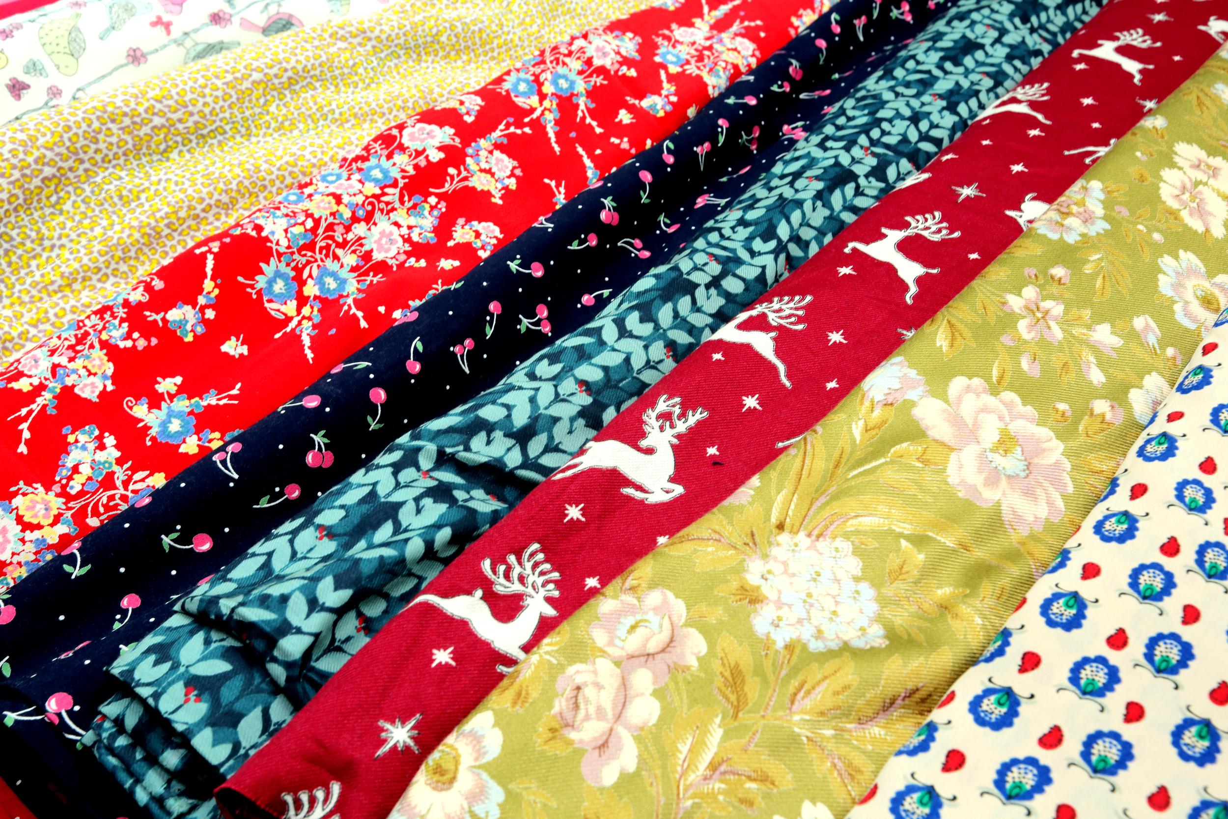 Several colorful fabric rolls with floral, reindeer, and cherry patterns.