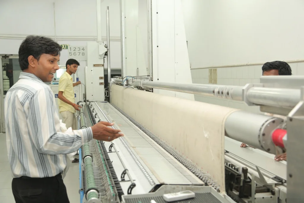 Three men working with a large machine in an industrial setting.