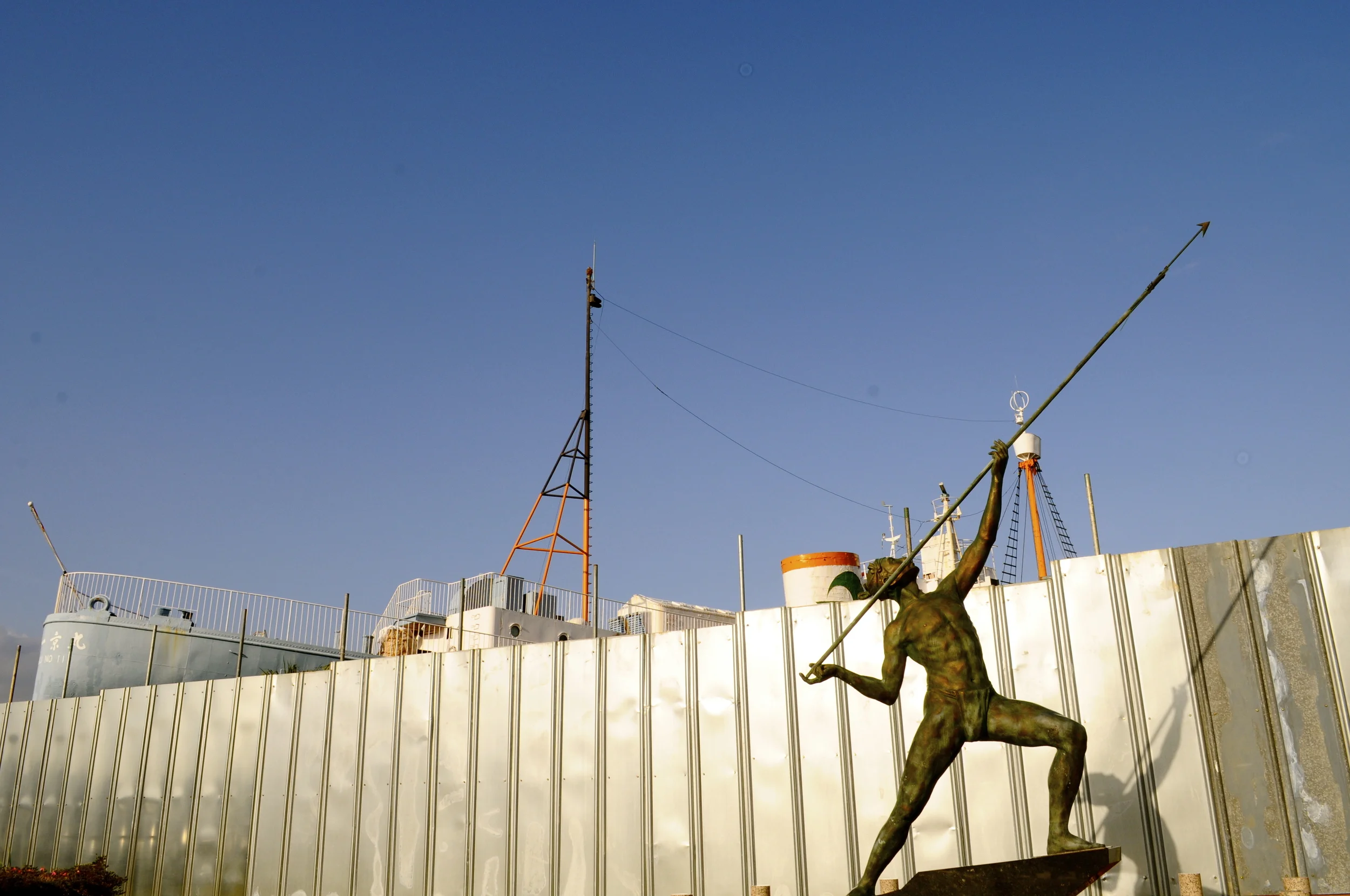 Traditional harpooner with modern whaling ship in background - Taiji, Japan