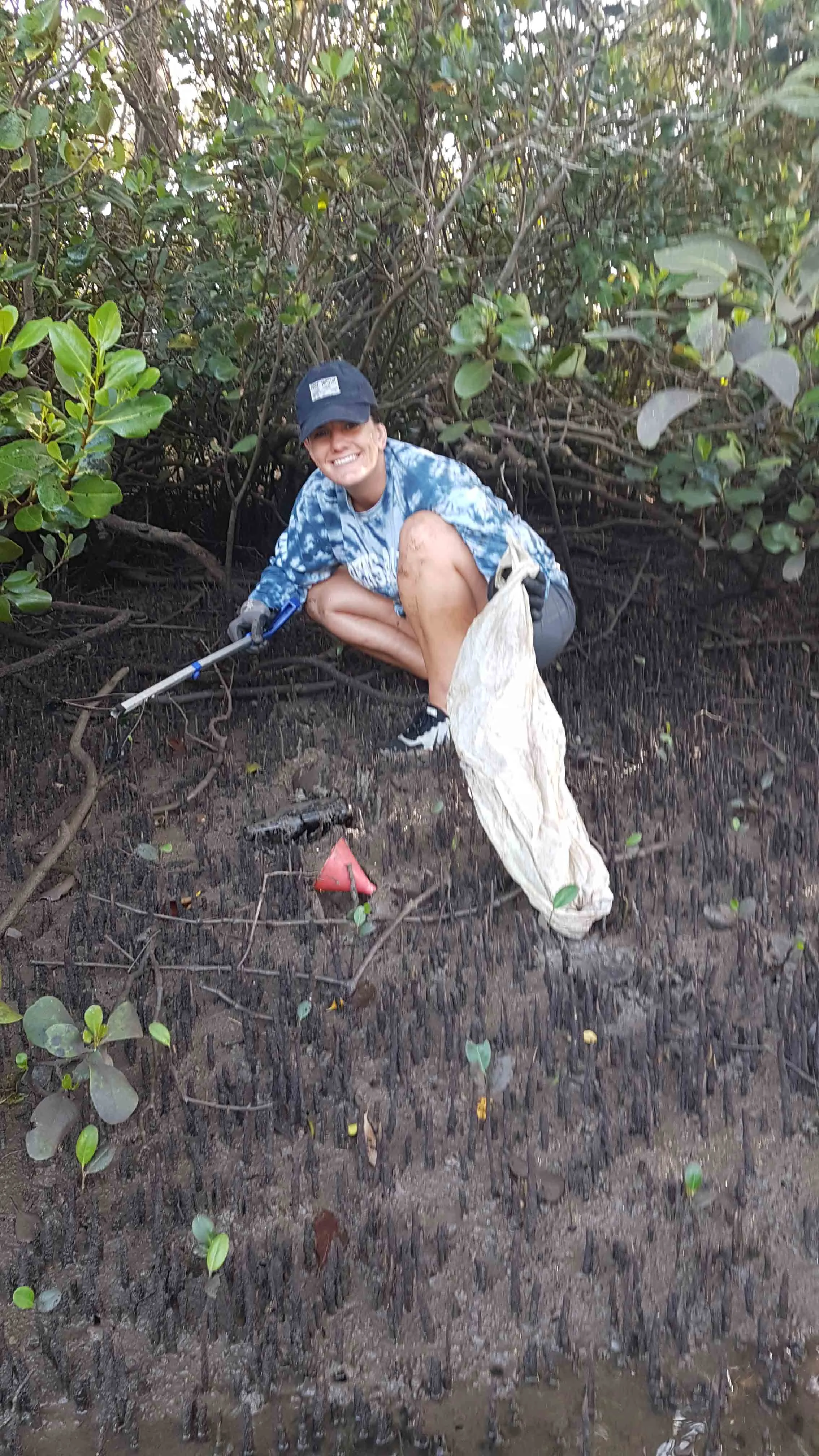 Brittany finding a pile of trash amongst the mangroves.